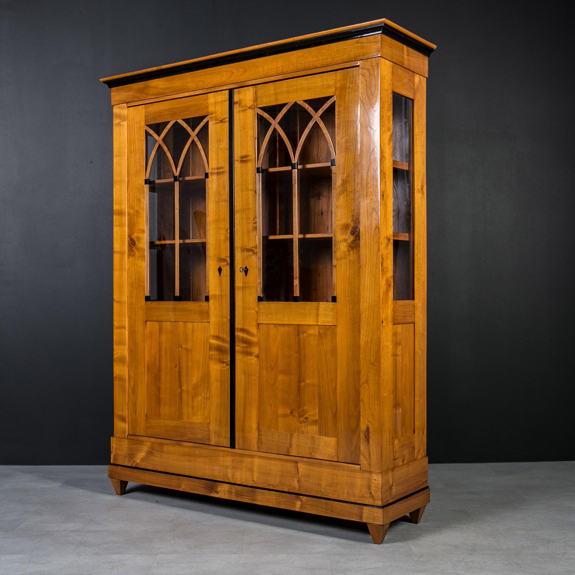 This beautiful vitrine comes from Germany and was made in 19th century, the Biedermeier period, showcasing a craftsmanship that stands the test of time.  The construction is made of solid cherrywood. Behind the doors lockable with a key you will