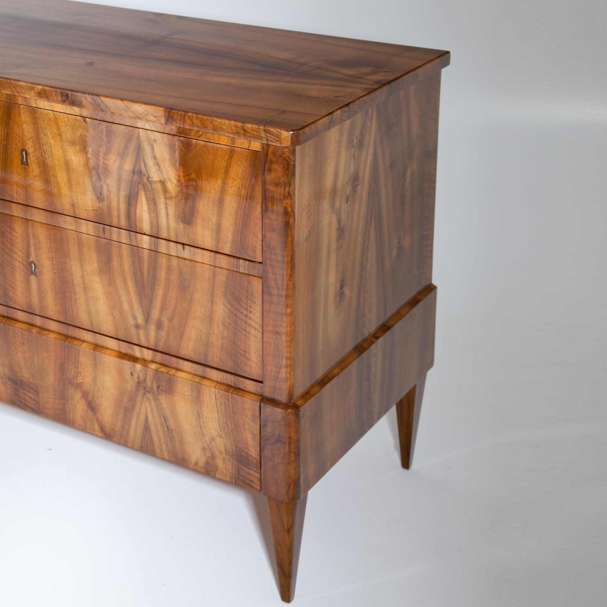 Biedermeier chest of drawers with three drawers on square pointed feet. The lowest drawer blends into the slightly accentuated all-round rail. Very nice walnut veneer. Restored condition, legs replaced.