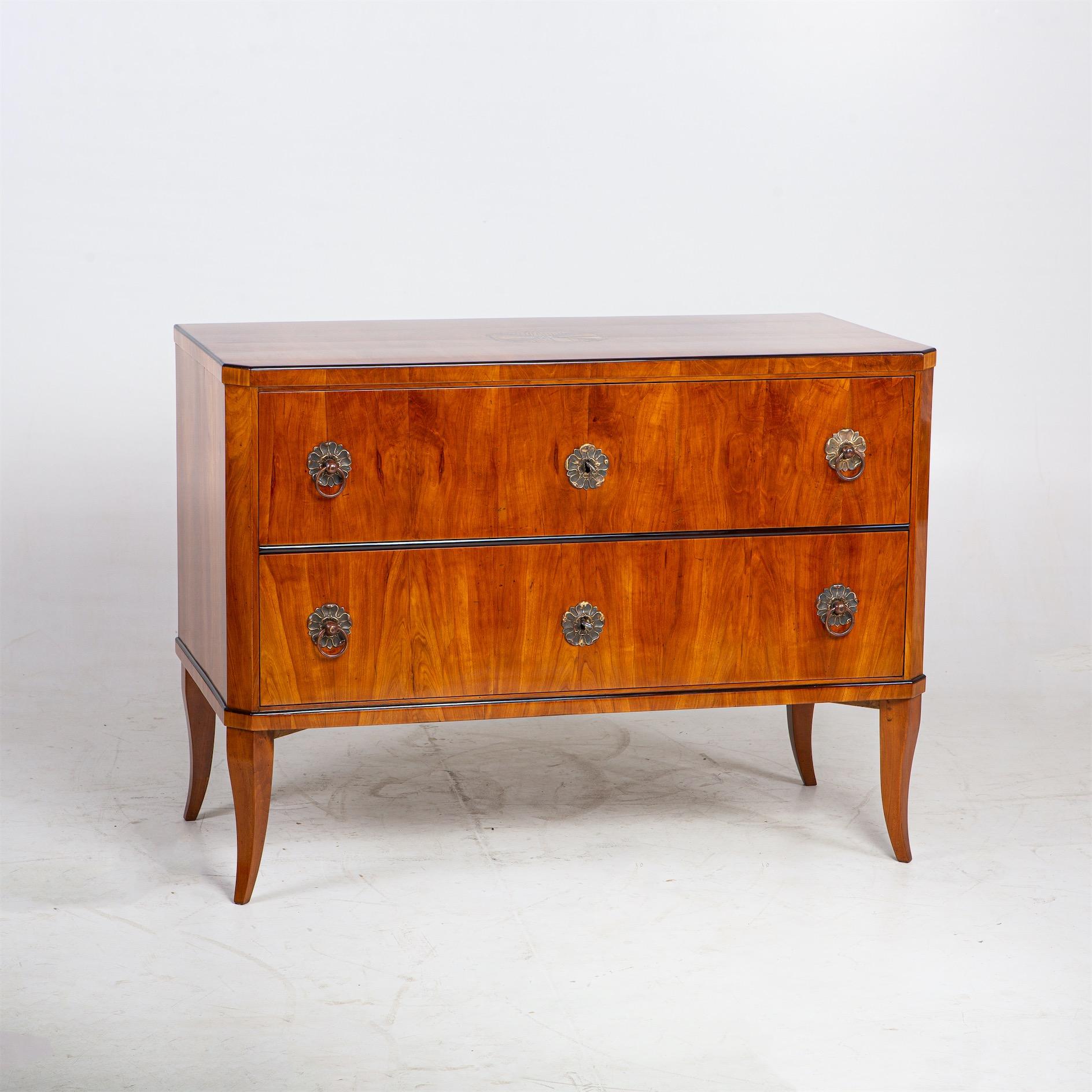 Biedermeier chest of drawers on elegantly curved legs with two drawers and straight-lined body veneered in cherry. The chest of drawers has been expertly refinished and hand polished.
  