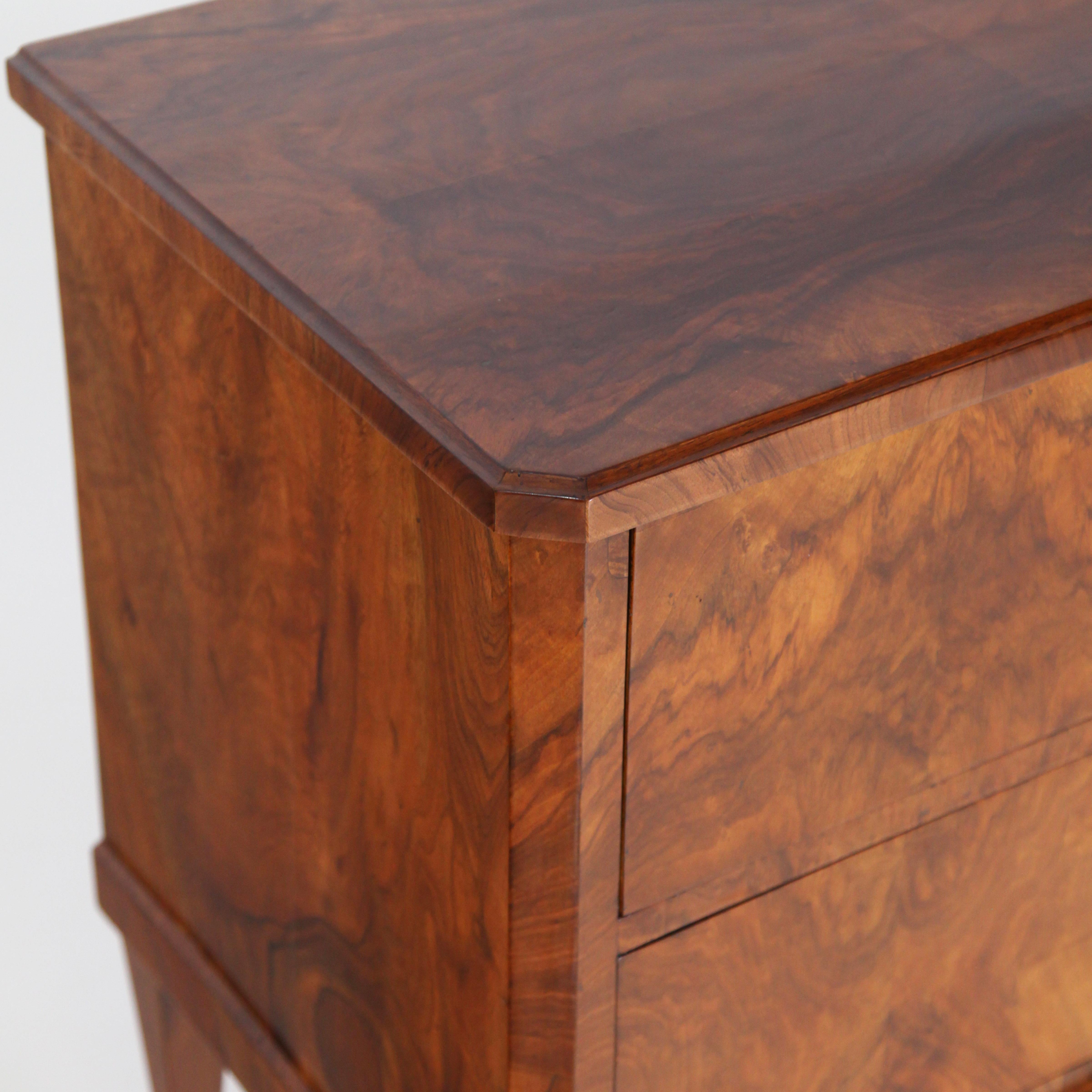 Two-drawered chest of drawers standing on pentagonal pointed feet with bevelled corners and very beautiful flamed walnut veneer. The keyholes with original leather fittings. Very nice restored and hand polished condition.
  