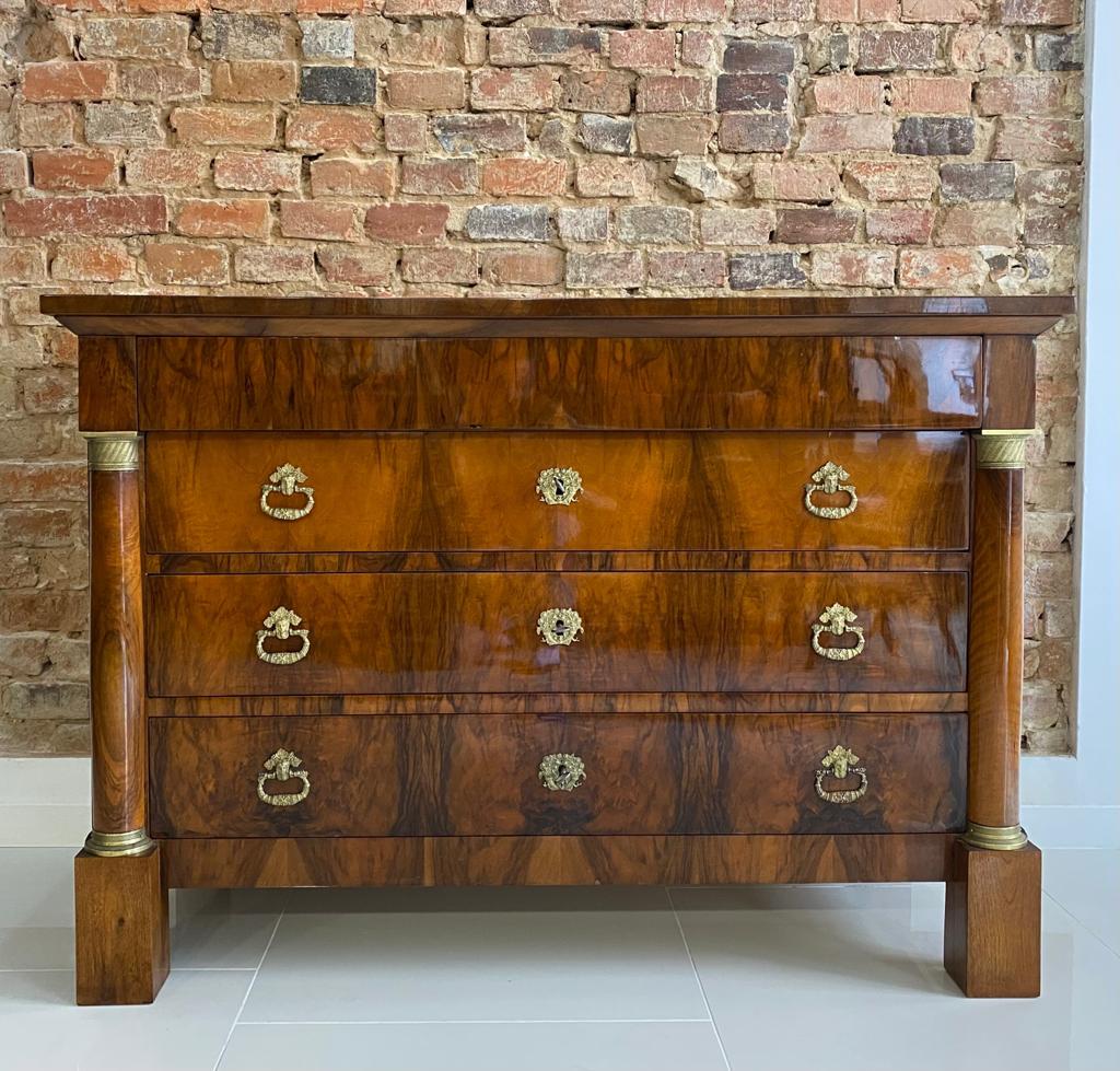 Biedermeier chest of drawers from 19th century, circa 1830s. This piece of furniture comes from France. It was made of softwood and veneered with beautiful walnut veneer. It is equipped with unique columns, decorated with brass decorations. It has