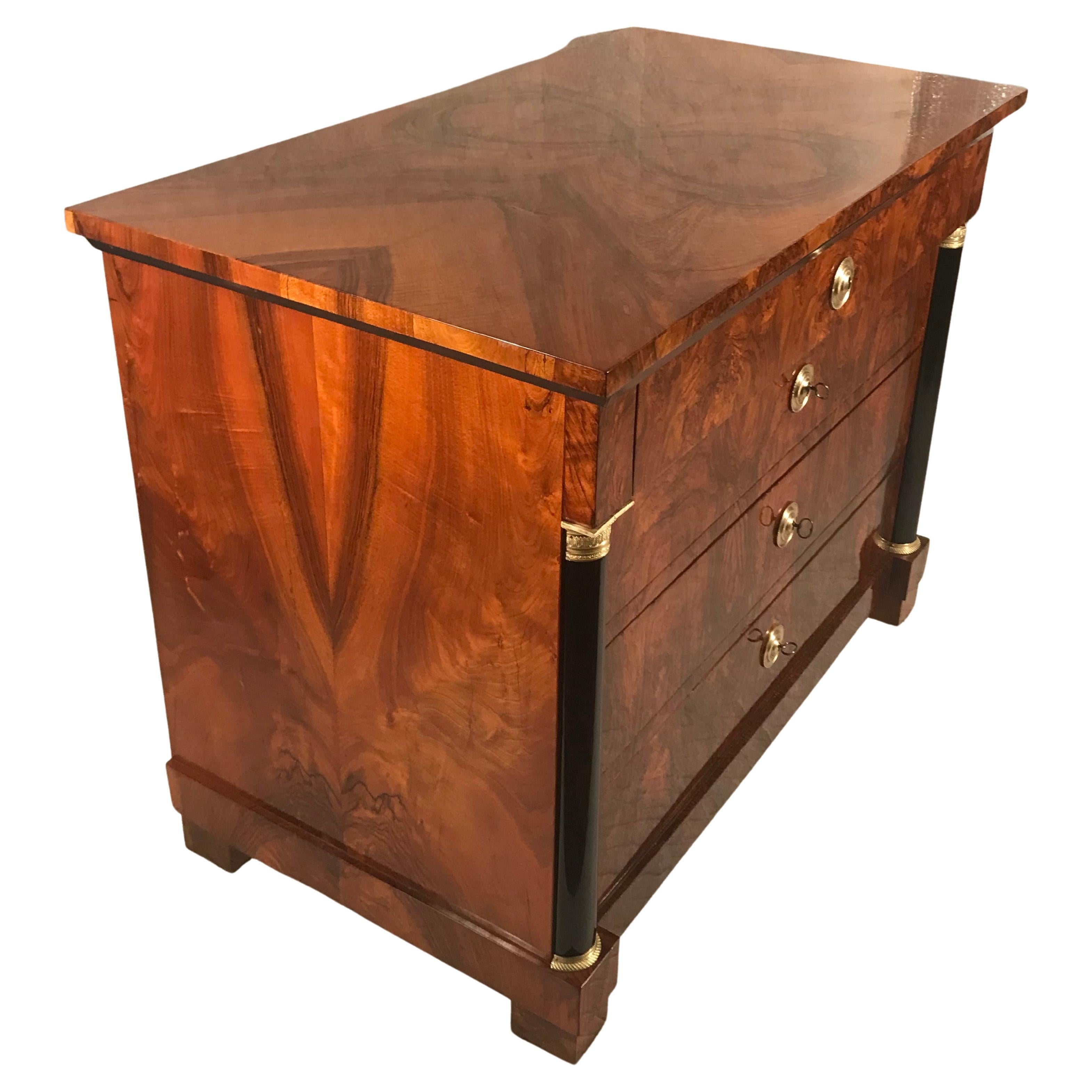 This original Biedermeier chest of drawers dates back to 1820 and was made in Southern Germany. The four drawer commode has a gorgeous walnut veneer. The uppermost drawer is slightly protruding and the three lower drawers are flanked by two ebonized