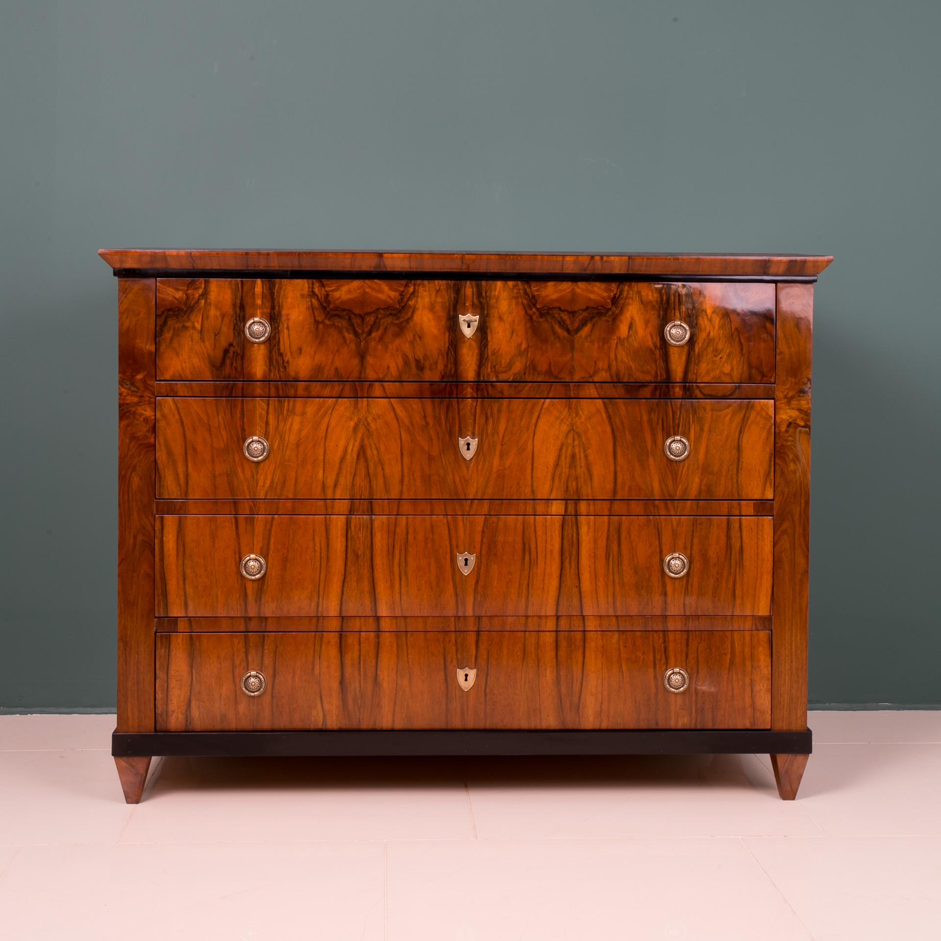 Biedermeier style chest of drawers from 19th century, circa 1830s. This piece of furniture comes from Germany. It was made of coniferous wood and veneered with beautiful walnut wood. It features 4 spacious drawers. The chest of drawers has undergone
