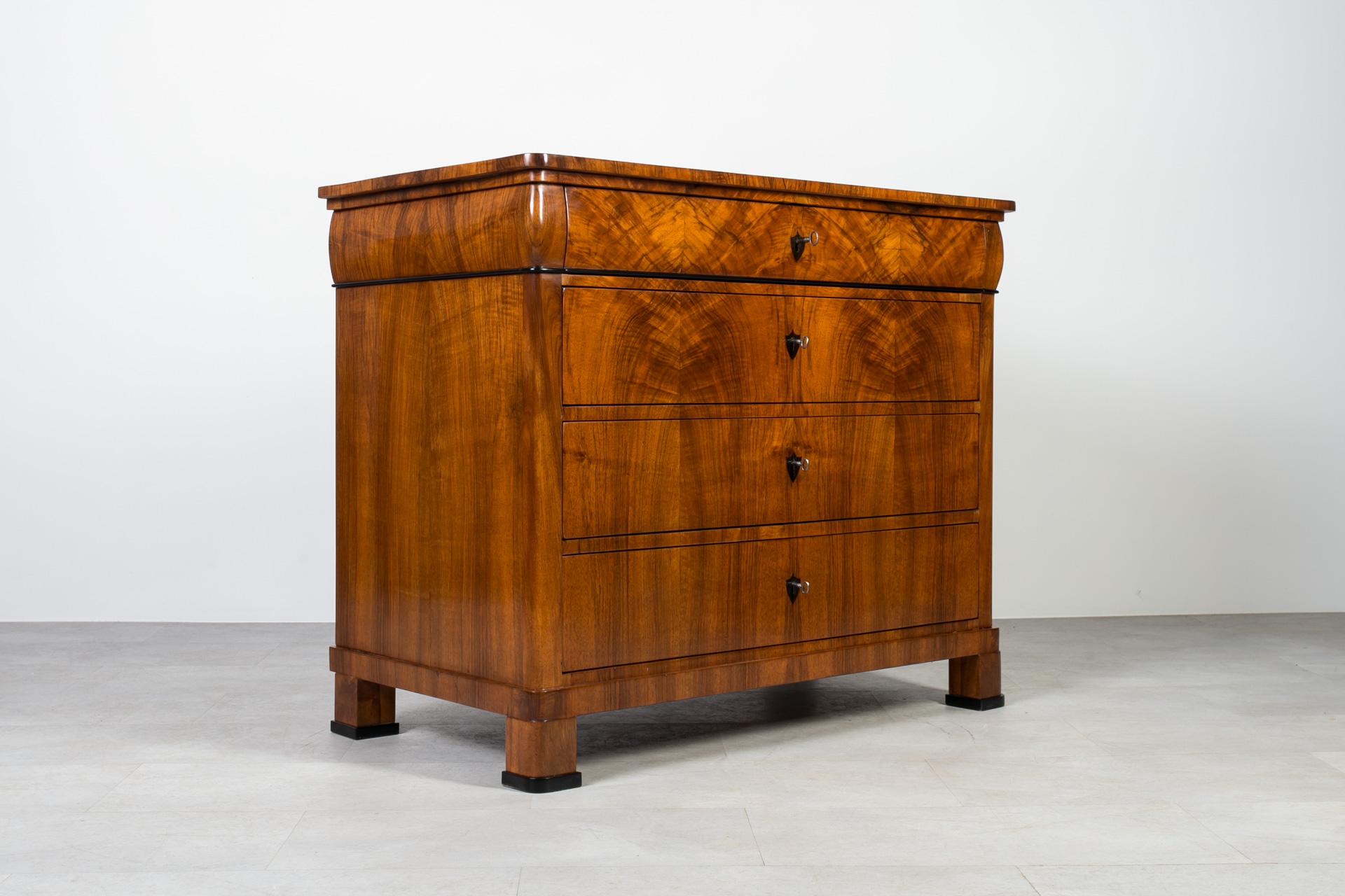 This Biedermeier chest of drawers was made in the 19th Century, originating from Germany. Crafted with precision and attention to details, construction made of pine wood adorned with exceptional walnut veneer. Admire its distinguished features,