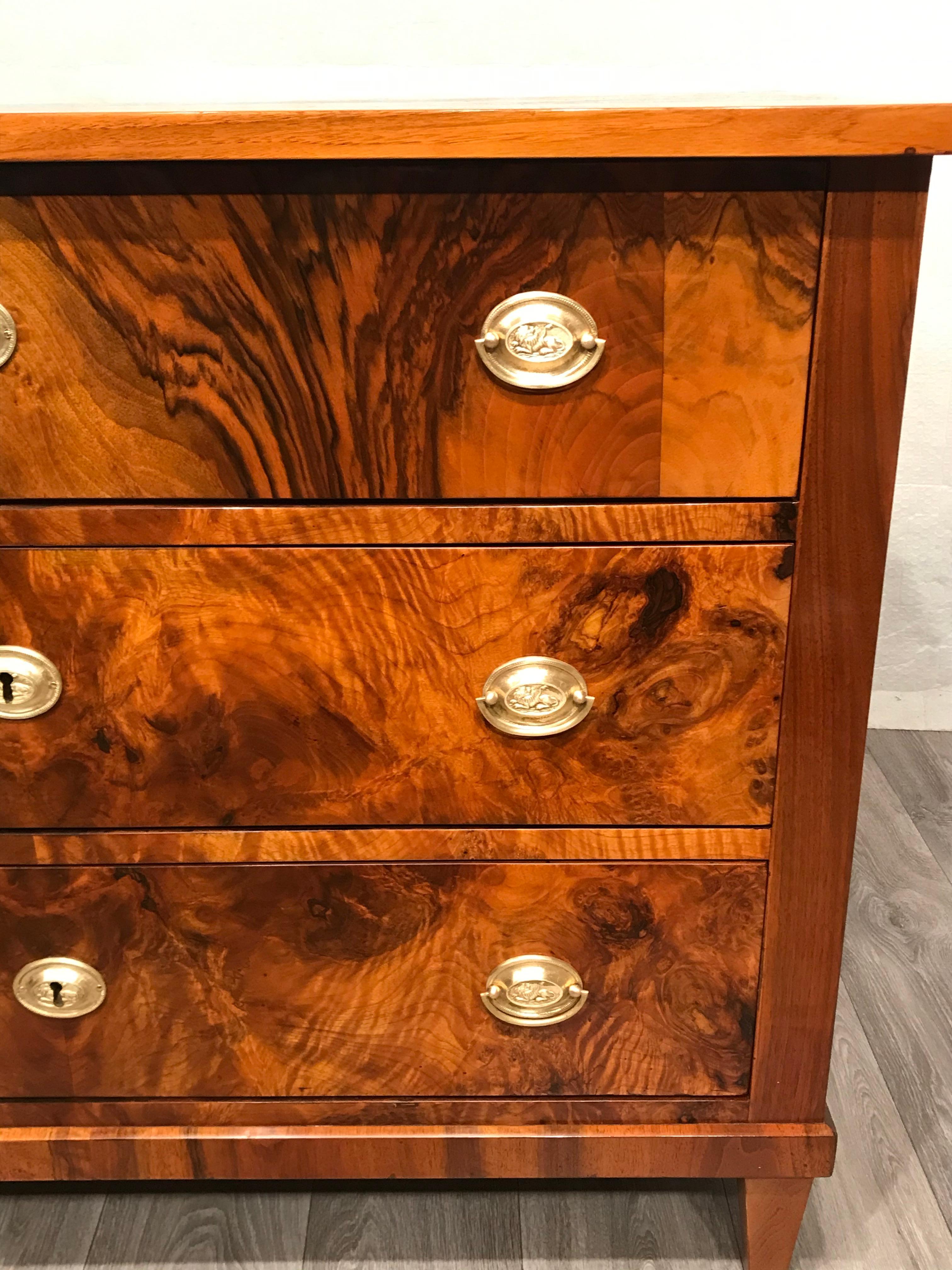This Biedermeier chest of drawers is embellished with a beautiful walnut veneer. 
The three drawer commode offers a lot of storage space and stands out for its unpretentious and elegant design.
The chest of drawers is in very good refinished
