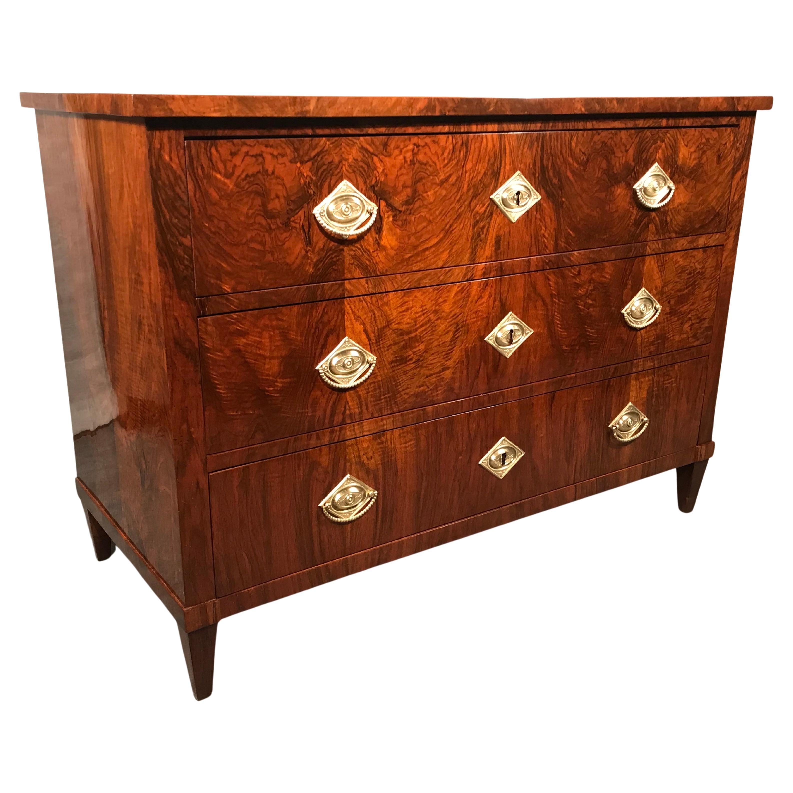 This original 1820's Biedermeier Chest of drawers comes from Southern Germany. The three drawer dresser stands out for its sleek design and the beautiful walnut veneer. It stands on four pointed feet.
The dresser comes refinished and French