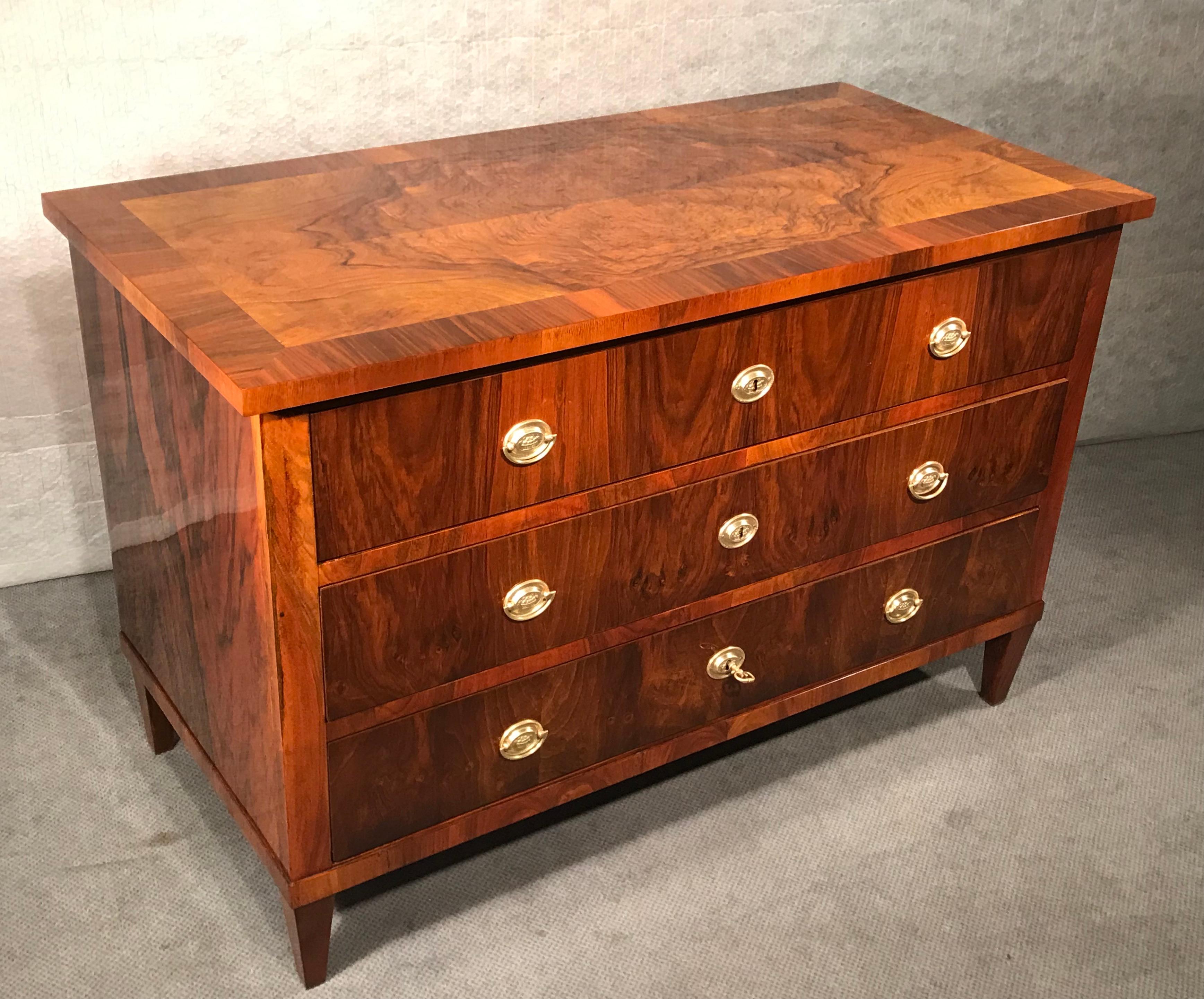 This classic Biedermeier chest of drawers dates back to 1820 and comes from Southern Germany. The three drawer commode features an unpretentious design and stands out for its very pretty walnut veneer. Especially the top has a very unusual veneer