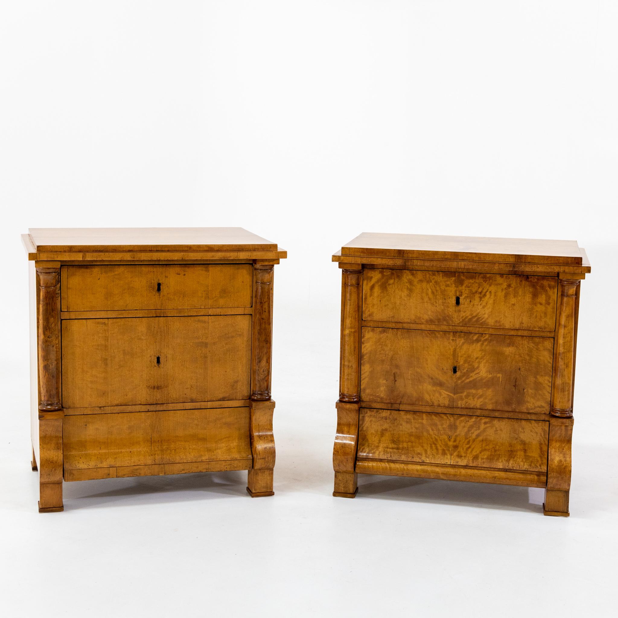 Pair of Biedermeier chests of drawers with three drawers and half pillars on square feet. The pilasters rest on volutes in the lower third. The chests are veneered in birch, restored and hand polished.