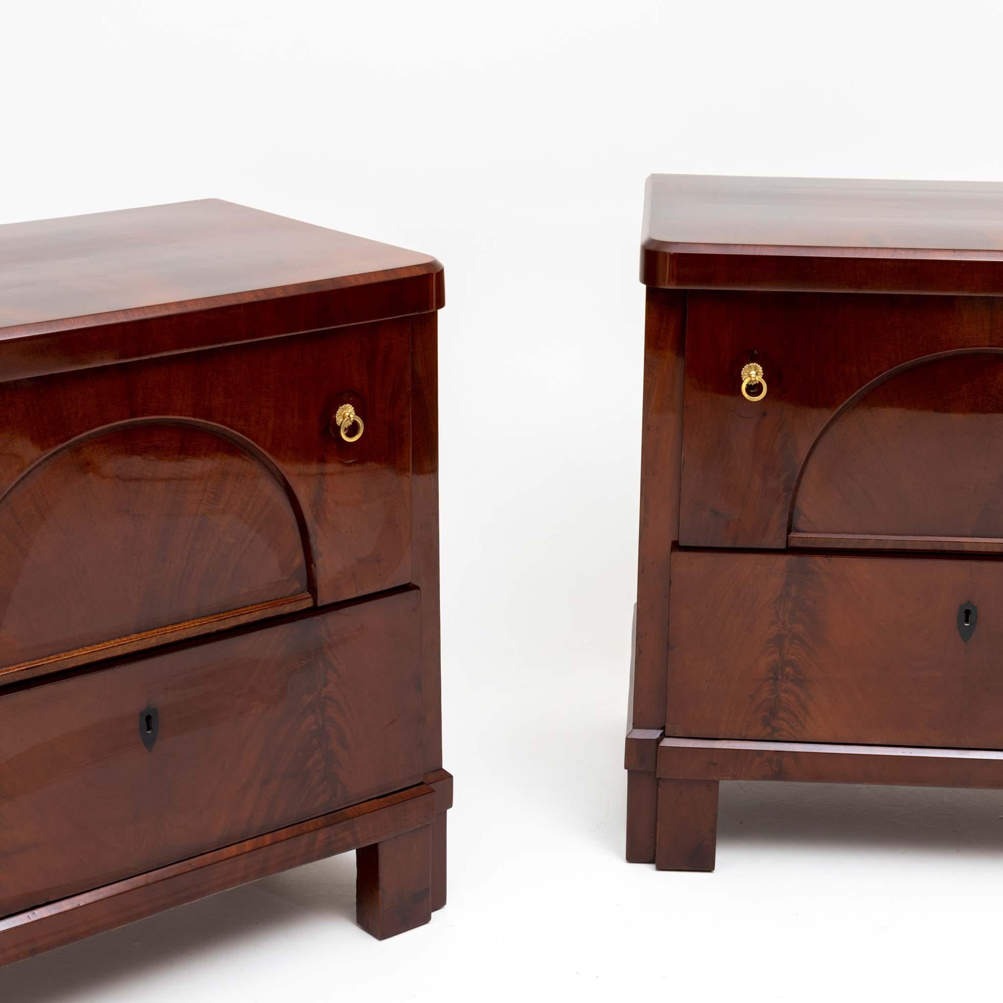 Pair of Biedermeier chests of drawers in mahogany veneered, with two deep drawers and segmental filling field. The chests of drawers were professionally restored and hand polished. The fittings are secondary.