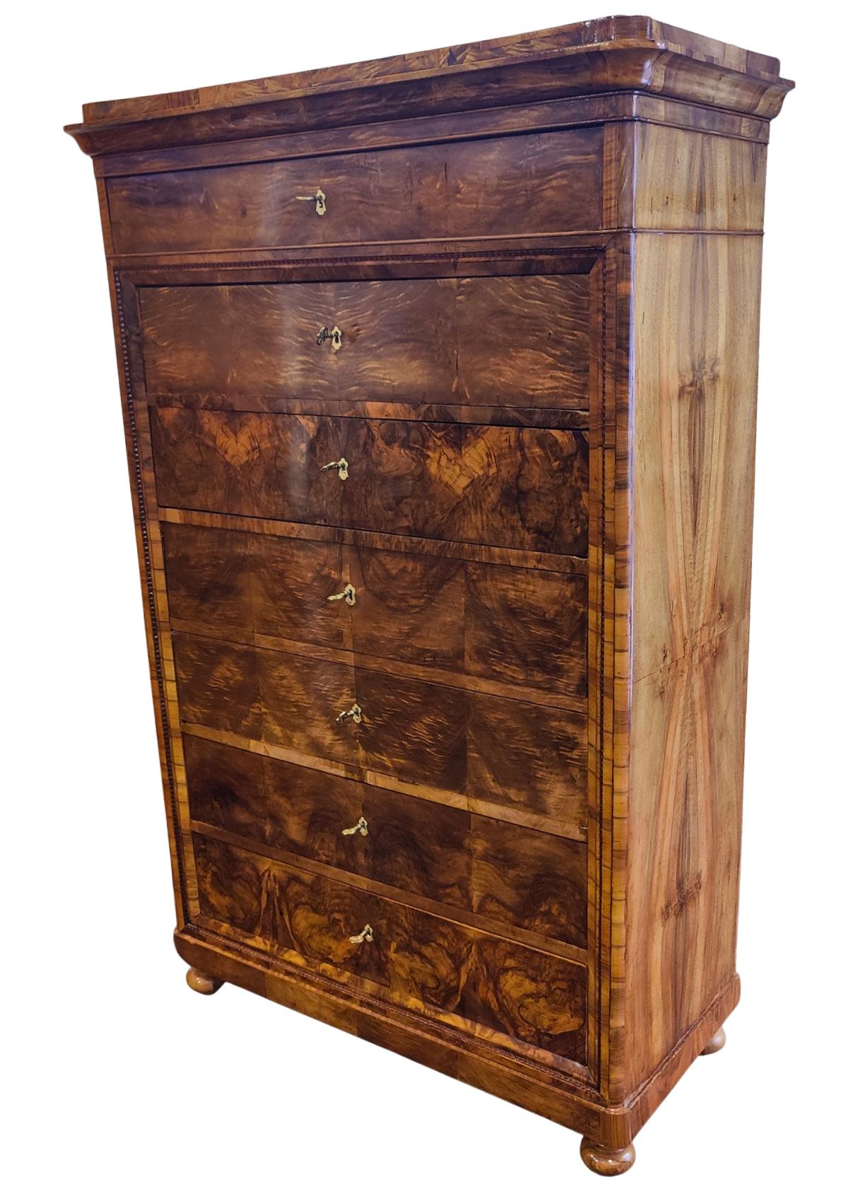 Cette élégante et rare chiffonnière Biedermeier a été fabriquée en Allemagne du Sud vers 1830. Il présente un placage de noyer magnifiquement grainé sur une carcasse en bois tendre, avec un remarquable motif de placage assorti sur la face avant. La