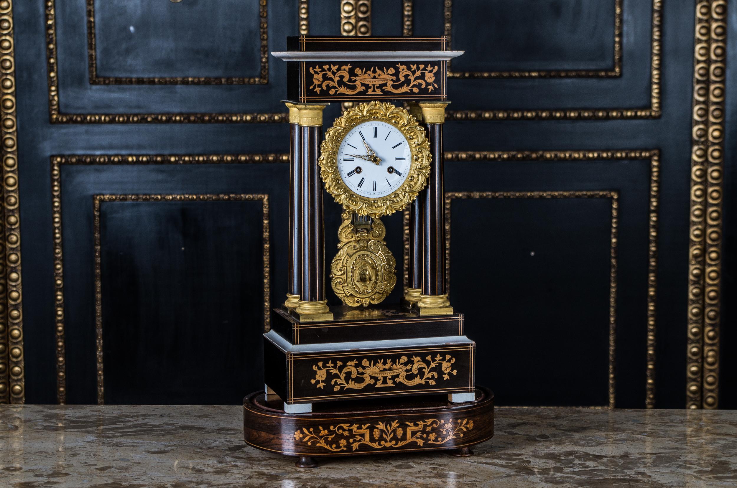 Rosewood with tendril and thread inserts. Rectangular base with four columns and the clock hung under the architrave. Dial Email. Gold-plated brass bezel and decorated gold compensation pendulum.