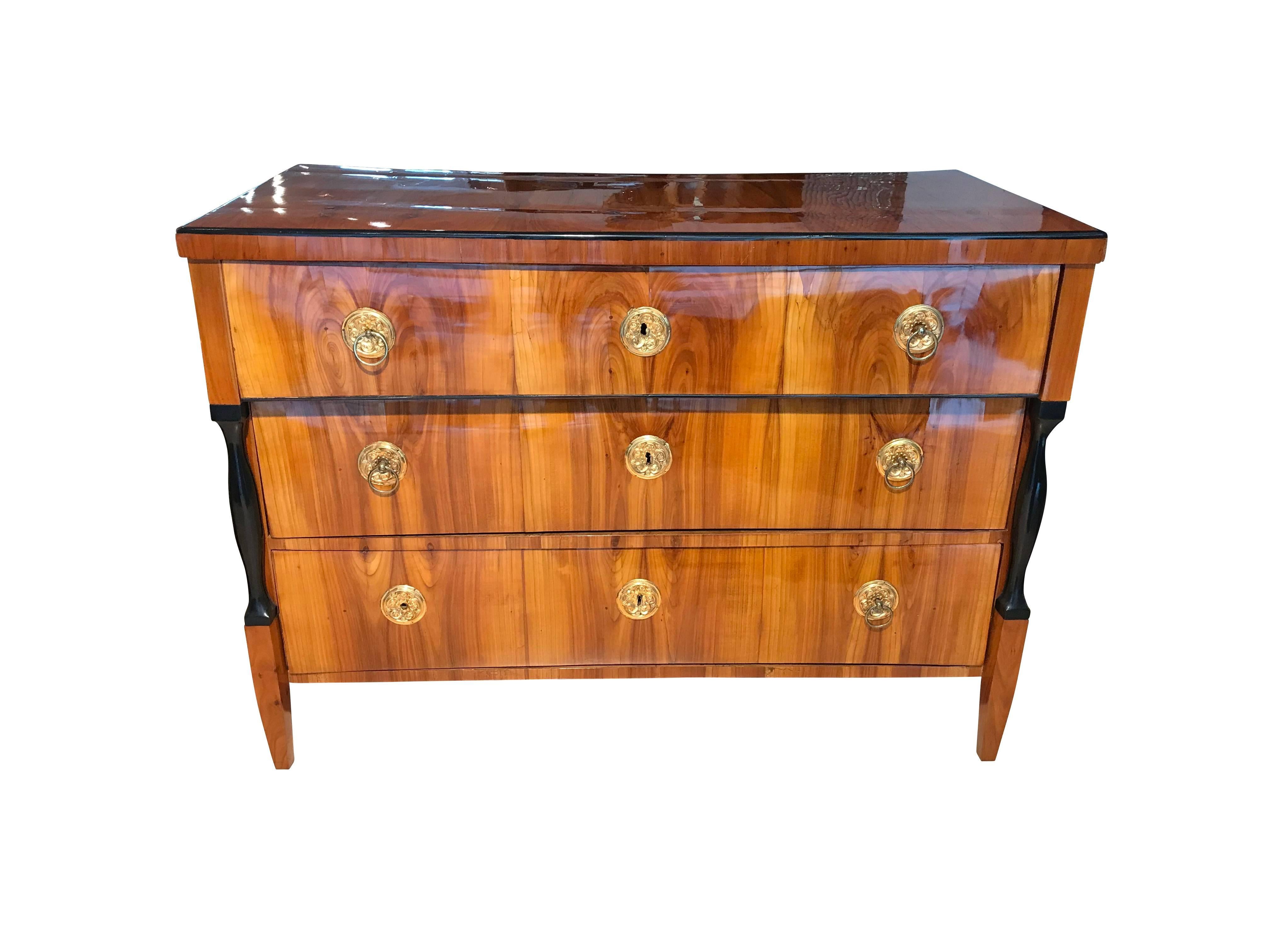 Wonderful, spacious neoclassical Biedermeier Commode / Chest of Three Drawers. Original brass hardware and beautiful cherry veneer. The two half-columns at the sides are ebonized. All the woodwork has been hand-polished with shellac (French Polish).