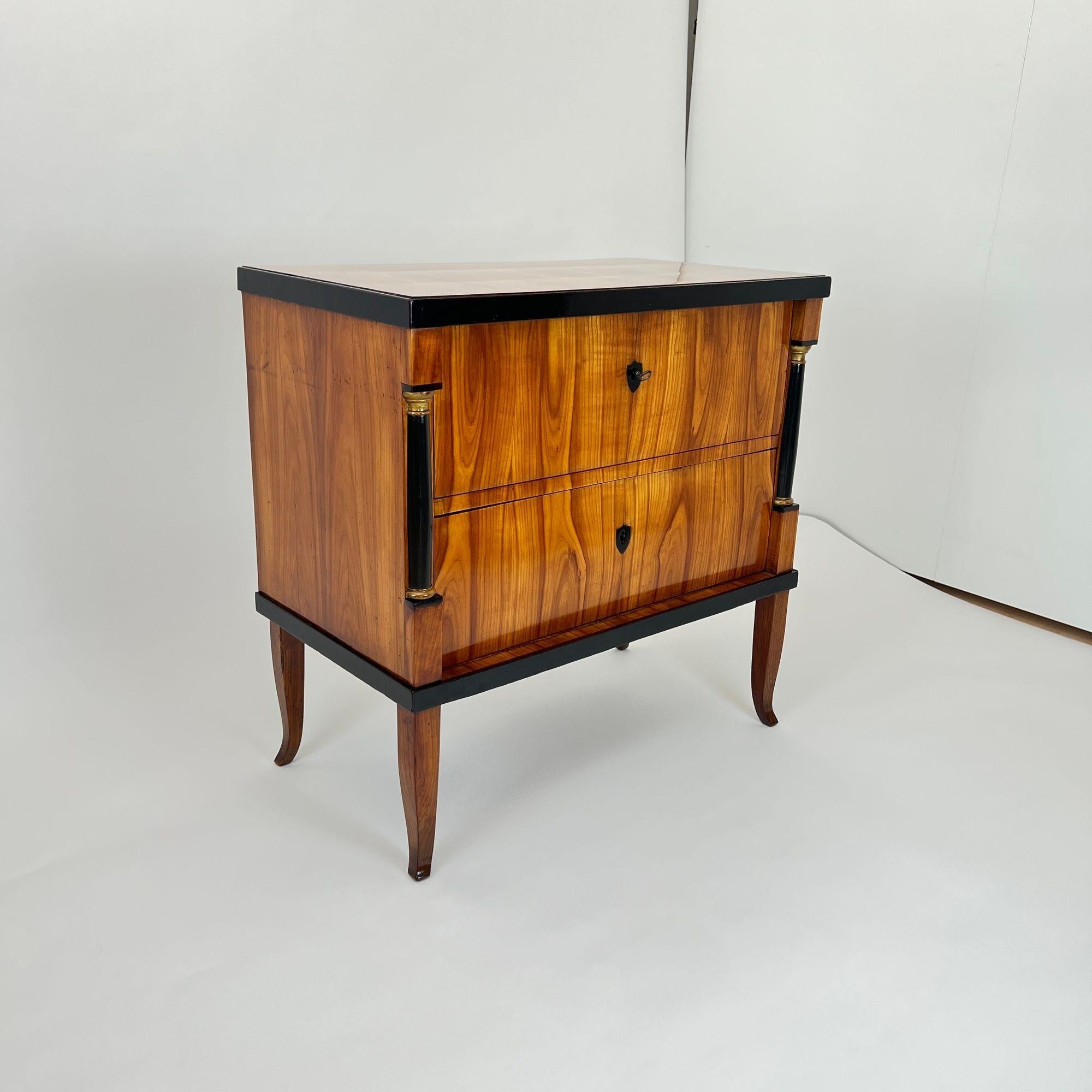 Magnificent, small, two-drawer Biedermeier commode or chest of drawers in cherry wood from Franconia around 1820.

Cherry veneered on softwood and solid. Standing on high, slightly curved square legs.
Ebonized trims, key crests and half columns. Old