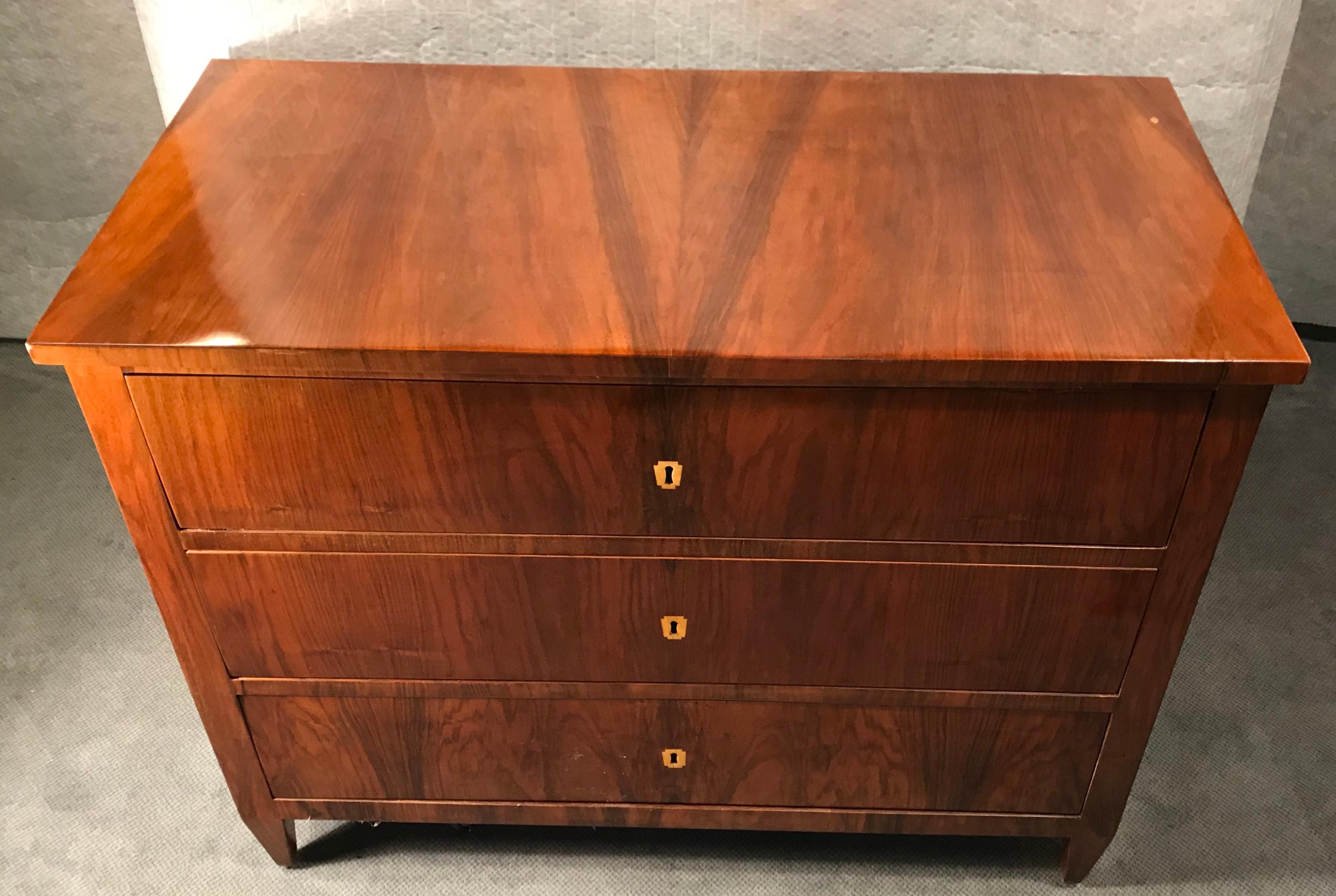 Original Biedermeier Commode, South German 1820. The commode or chest of drawers has a beautiful walnut veneer and inlaid bone escutcheons. It is in good condition. 

This is a very good example of the Classic, straight lined early Biedermeier