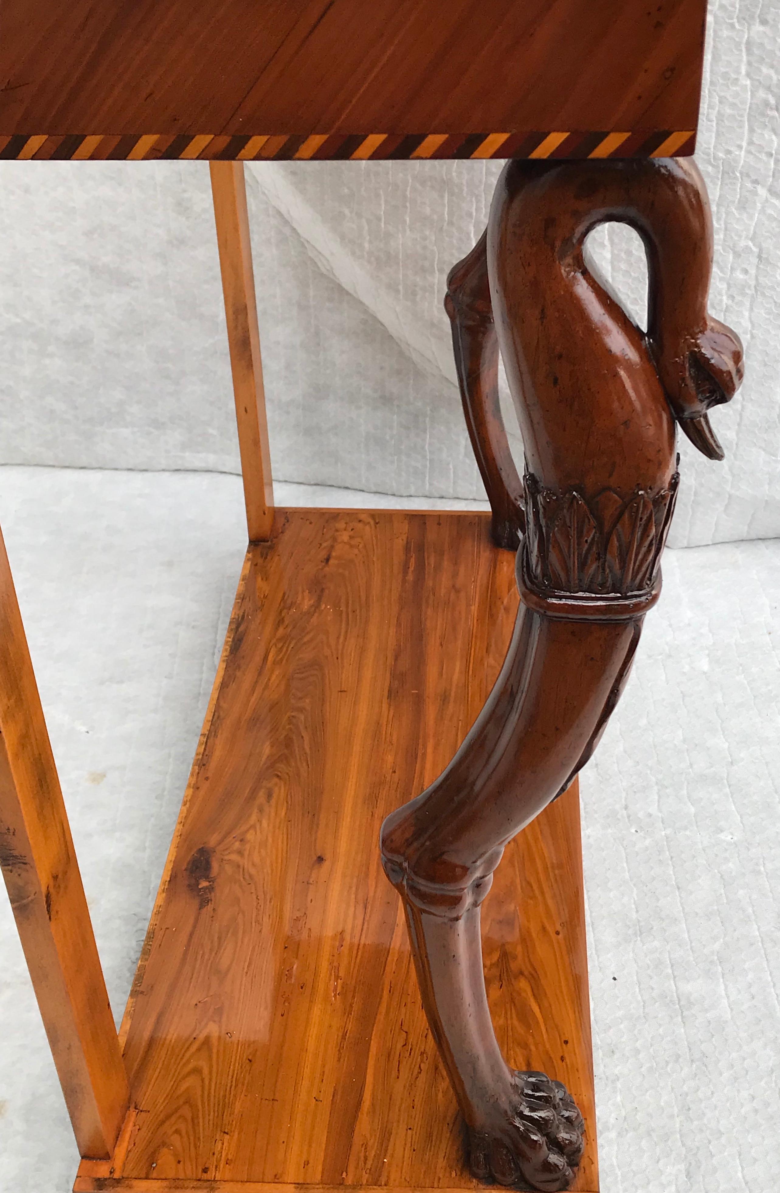 Biedermeier console table, Southern Germany 1820, cherrywood veneer with marquetry in mahogany and elmwood. Unique small console table, the front legs with beautiful carved swan heads. The table is in very good condition, refinished and French