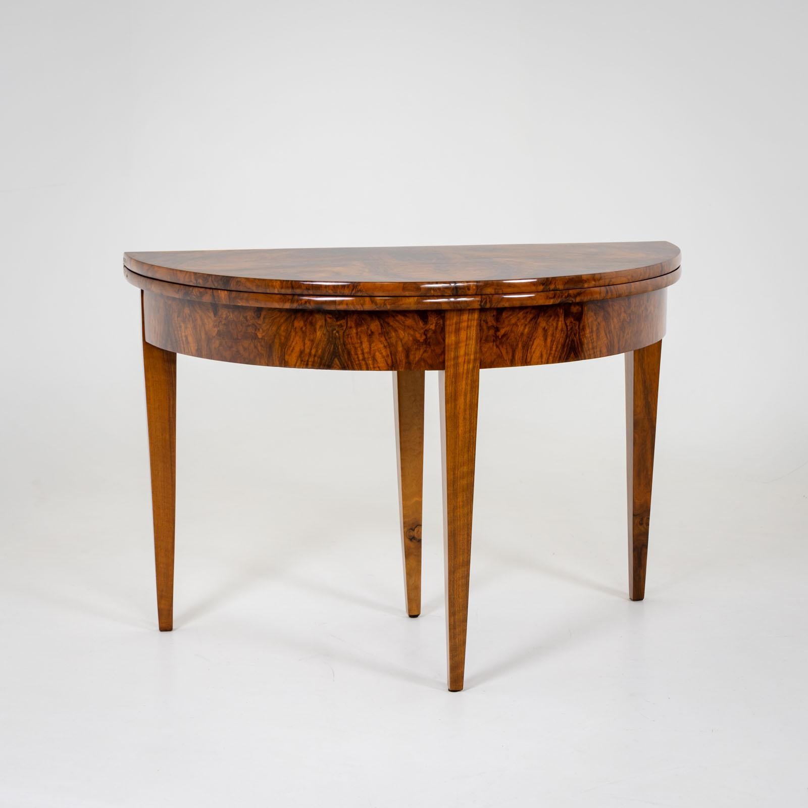 Elegant Demi-Lune console table on high square tapered legs. When opened, the table top rests on the extended rear leg with one drawer. The table is veneered in walnut and polished by hand. The table top is inlaid in a star shape in the center.