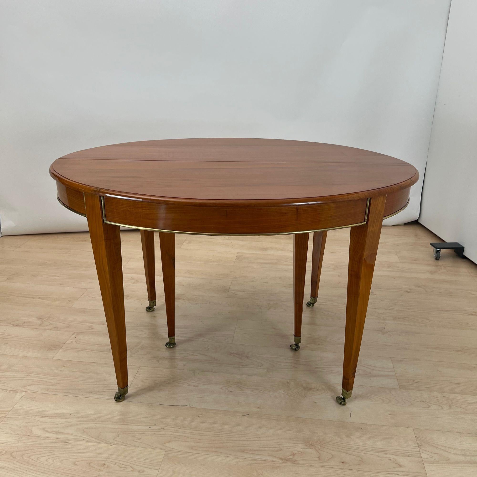 Biedermeier extending dining room table in cherry wood with brass bands from Southwest Germany around 1820.
Solid cherrywood top, strongly oval. Original, rounded brass bands around the apron. Six conical square tapers legs in solid cherry, with