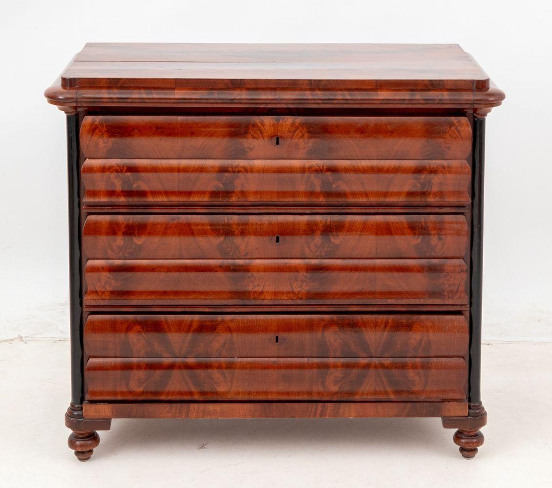 Biedermeier Kommode aus geflammtem Mahagoni, mit drei Schubladen, die von ebonisierten Säulen flankiert werden. 36