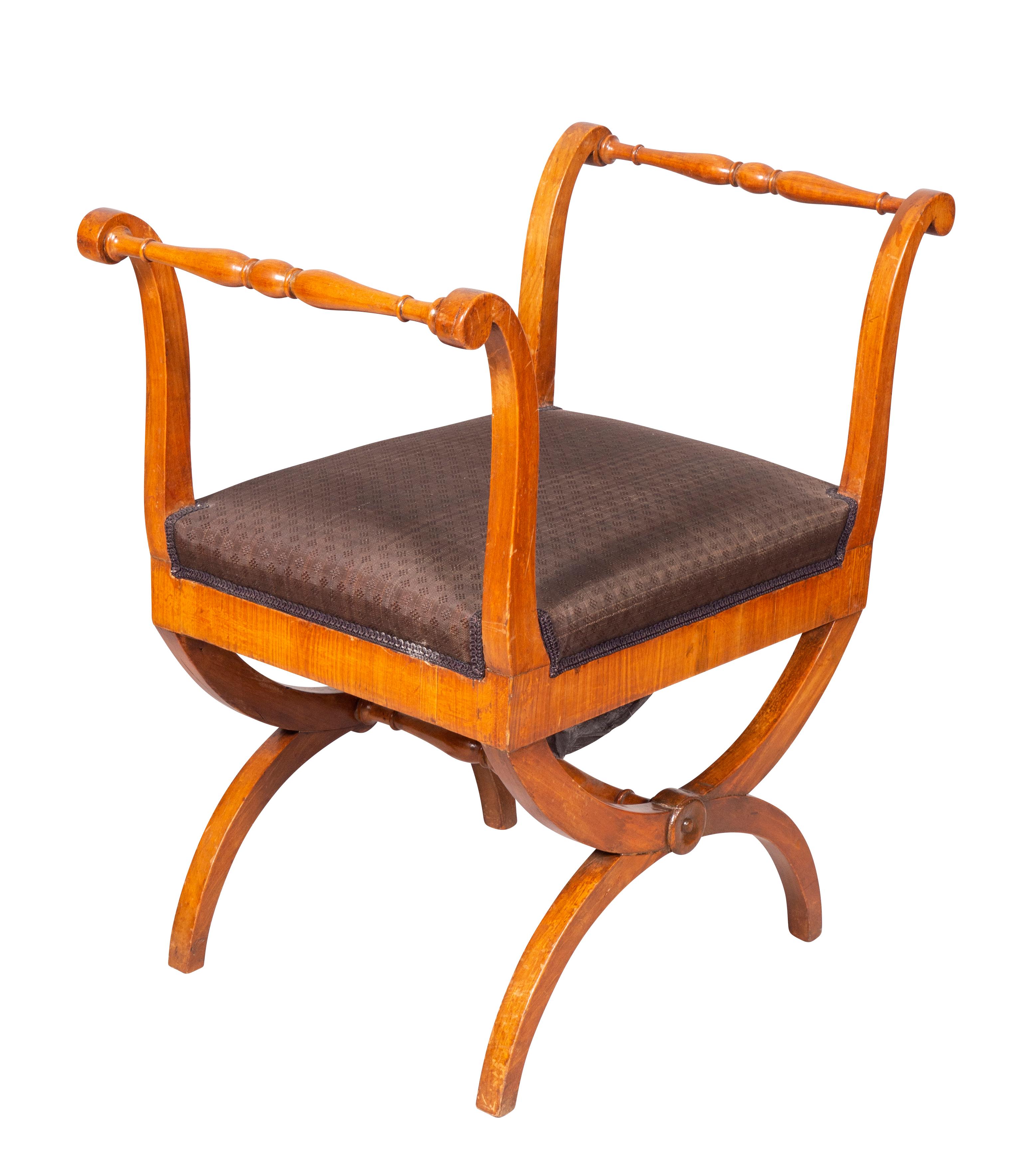 With tall scrolled sides with turned rails, upholstered seat raised on curule form legs.