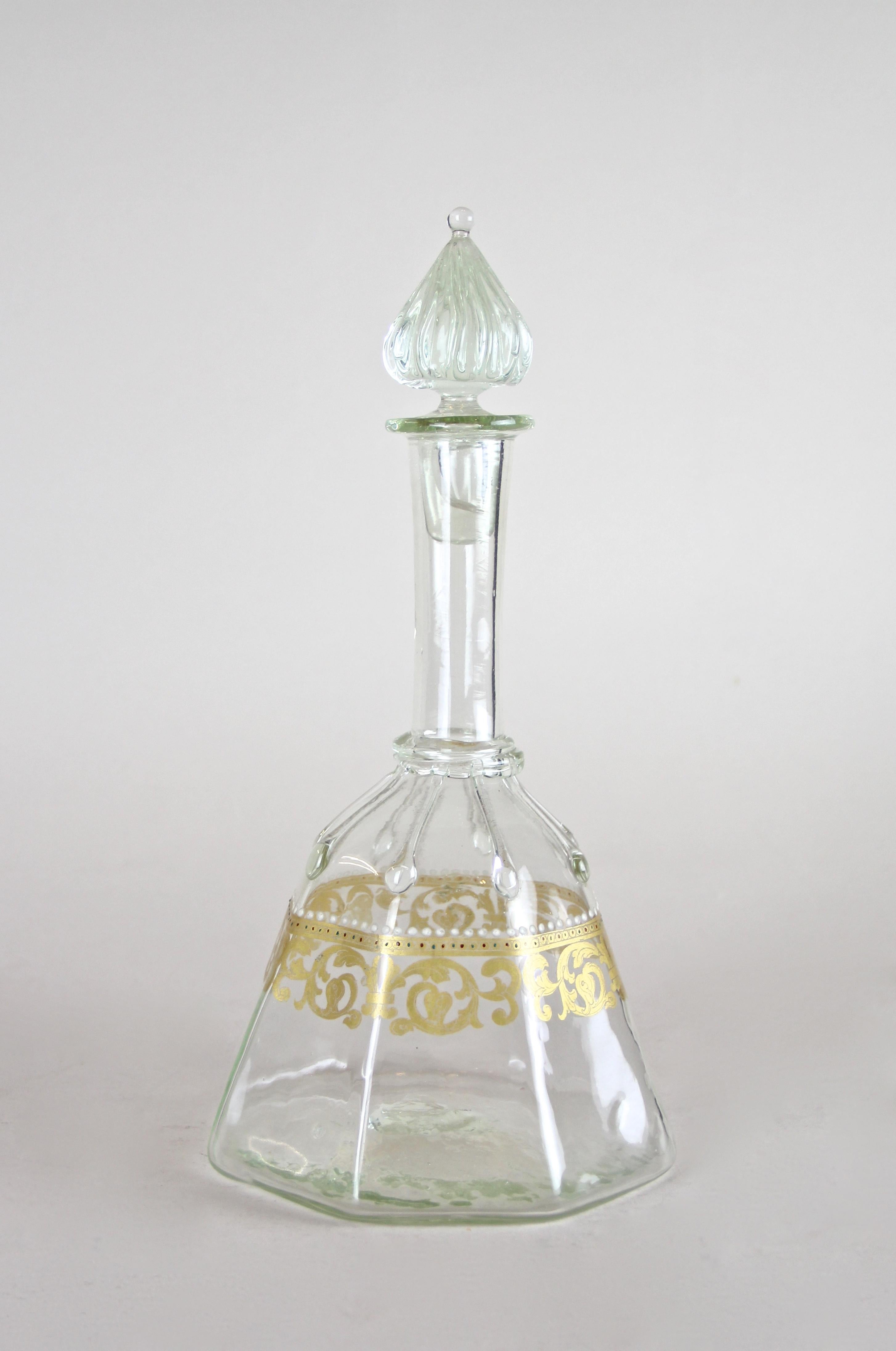 Graceful Austrian Biedermeier glass bottle with lid out of Vienna, the epicenter of this famous era. Made circa 1850, this decorative mouth blown glass bottle with a light green shine shows delicate golden design elements alongside very small enamel