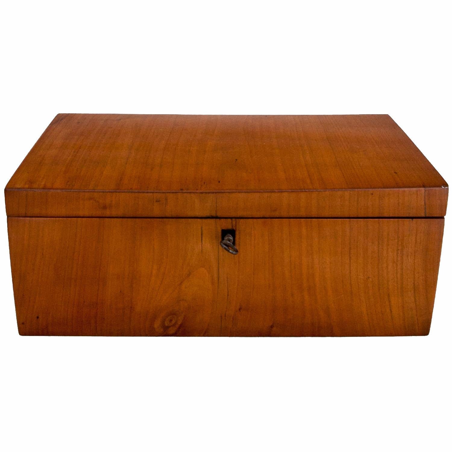 Lockable jewelry box or chest with a hinged lid and a smooth cherrywood corpus.