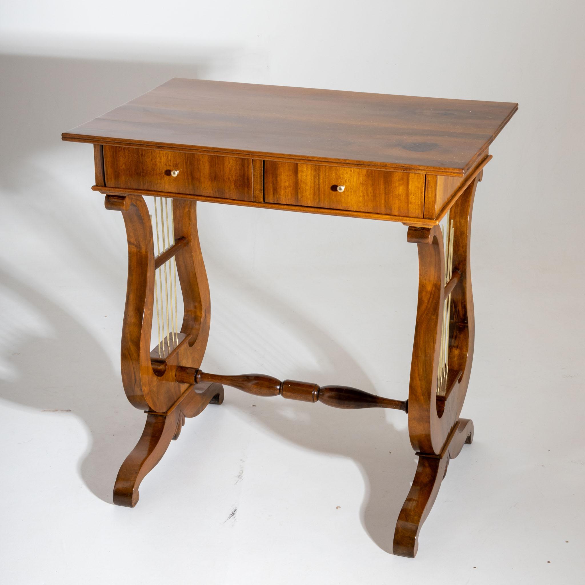 Biedermeier Arbeitstisch mit lyraförmigem Gestell und vier Schubladen. Der Tisch ist in Nussbaum furniert und handpoliert.