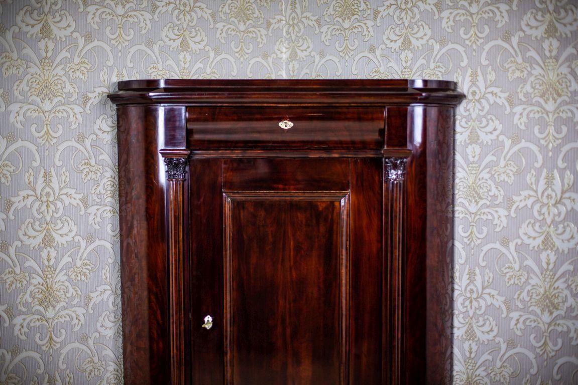 We present you a piece of furniture made of softwood veneered with mahogany.
The whole is circa 1870.
This cabinet is to be placed in the corner. It is single-leaf; with rounded corners, a topping board, and a cornice drawer and one under the