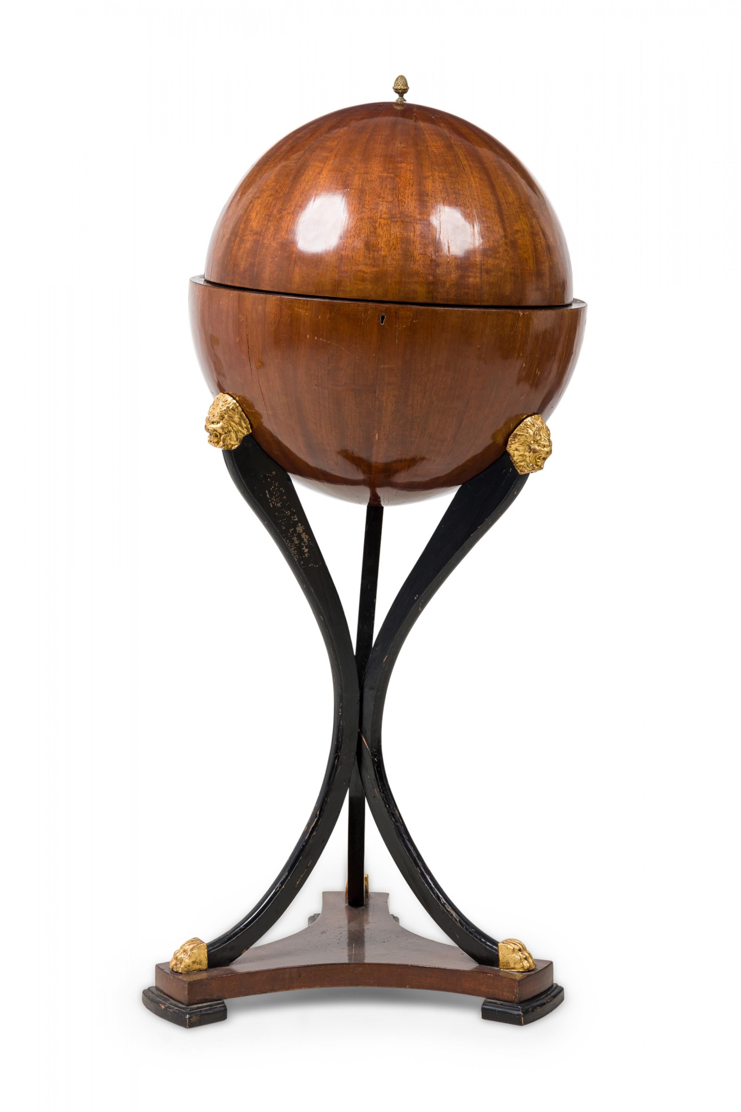 Biedermeier (19th Century) globe-form work desk with a mahogany structure that opens to reveal a several small compartments, with parcel gilt and ebonized detail, with applied lions\' head decorations at the top of each leg and a brass artichoke