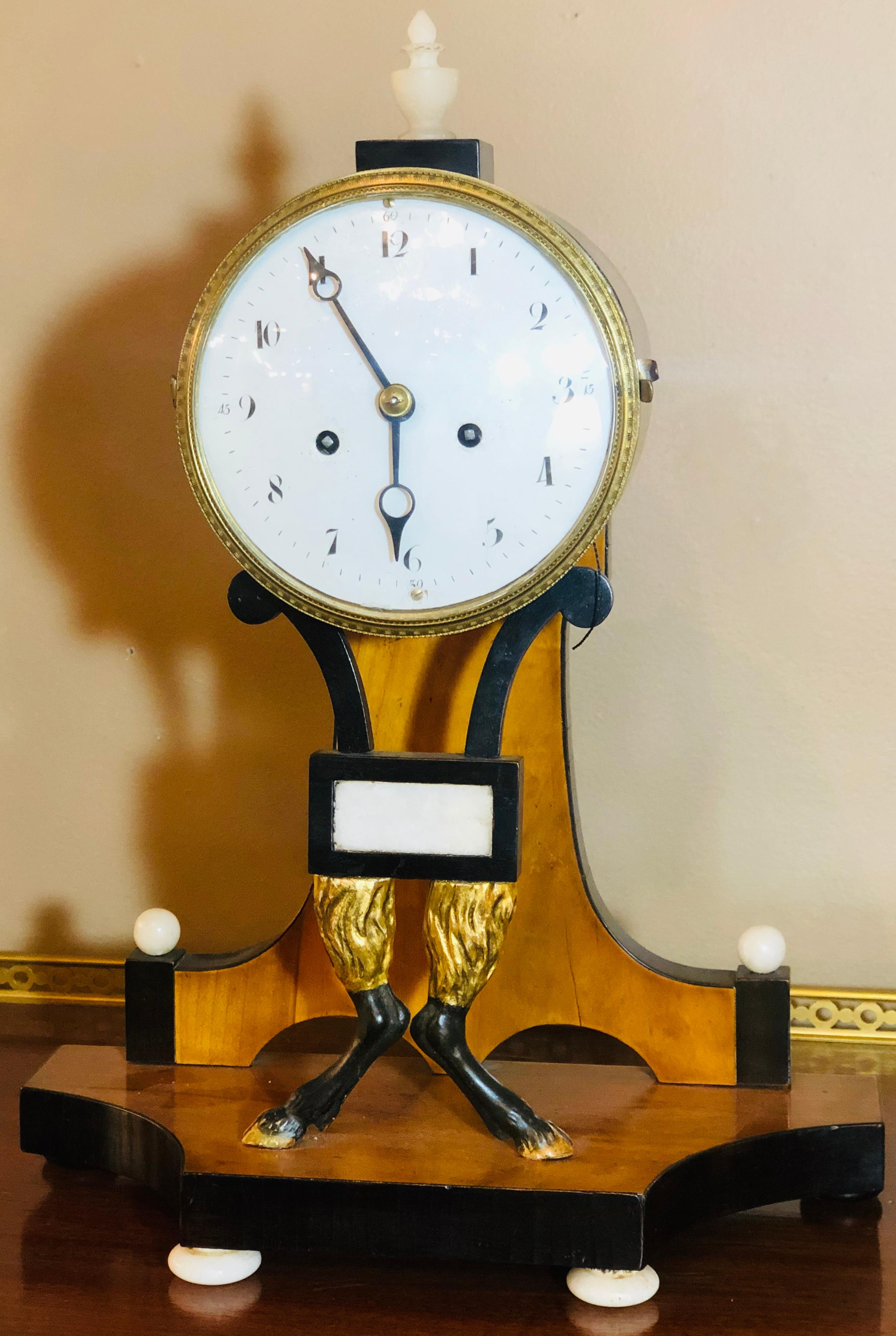 Fine Biedermeier clock with ebonized details and unusual hoof legs with silk suspension. Is in working order at time of listing, having pendulum and key. First quarter of the 19th century (1815-1848). This is a stunning example of Biedermeier at its