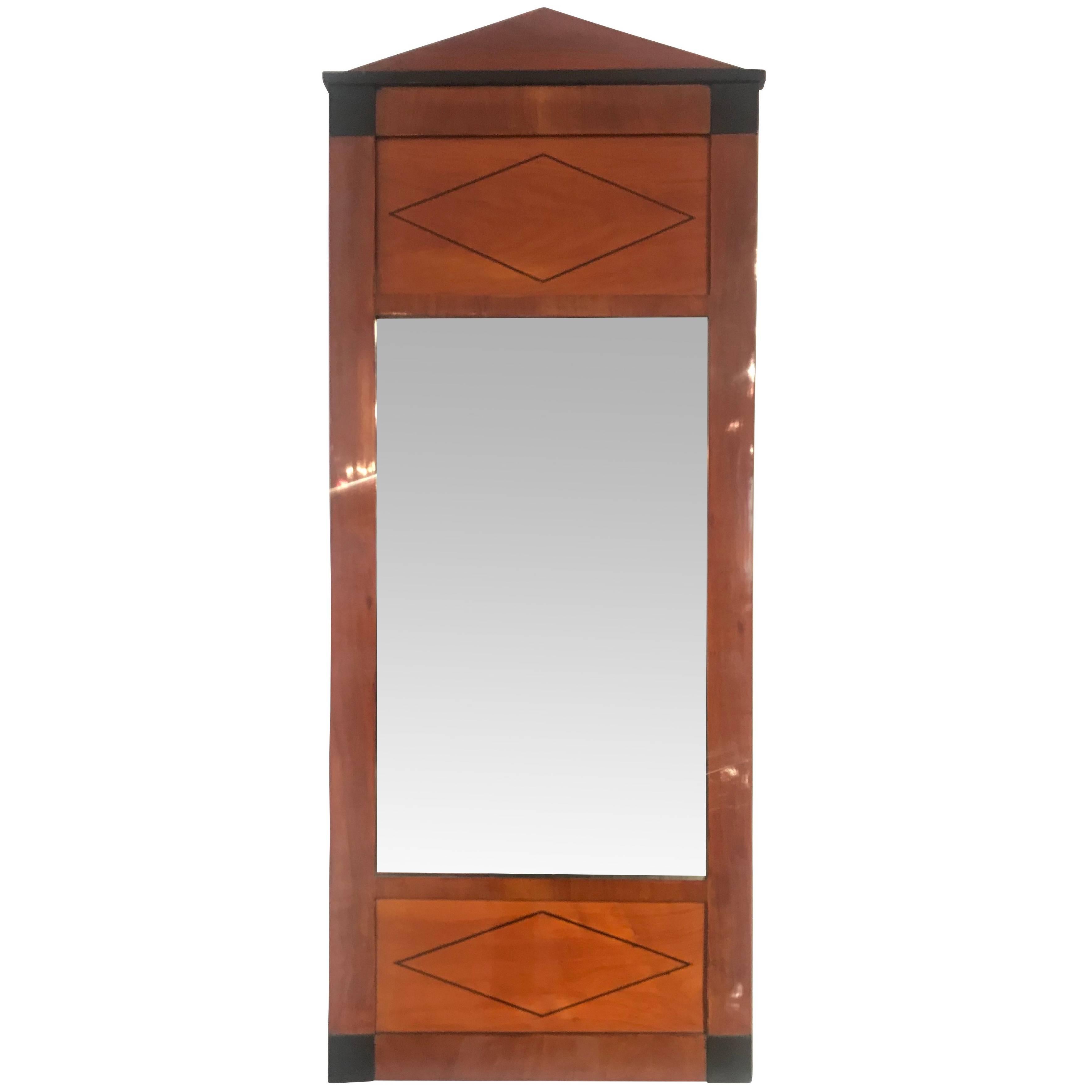 Very elegant classicist Biedermeier mirror in cherry veneer with ebonized parts. 

The hash at the top is made with an ebony inlay. 

The mirror glass is original. 