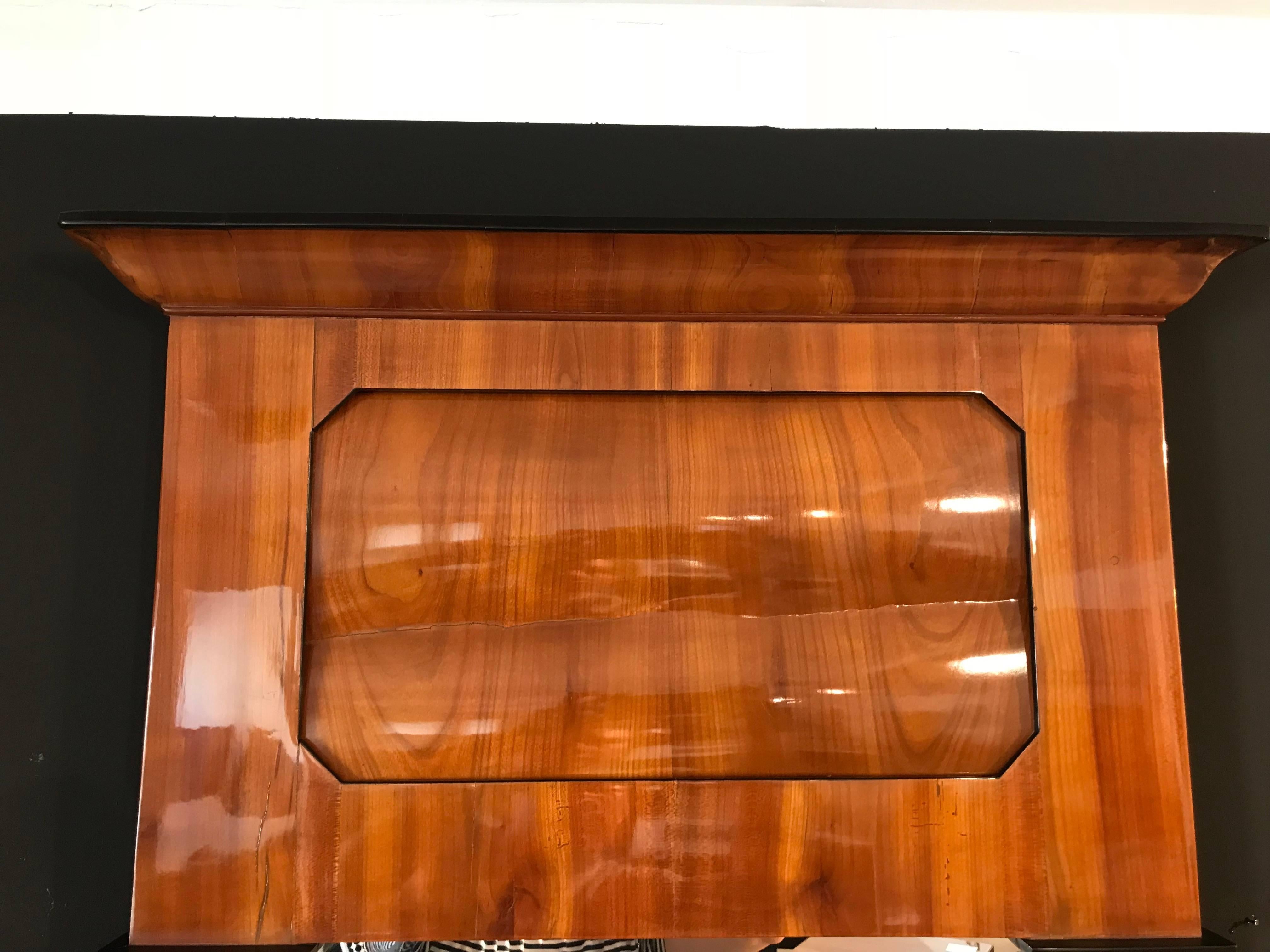 Very beautiful and elegant Biedermeier mirror with cherry veneer. It has some ebonized parts at the pilaster columns and original mirror glass. The wood has been hand-polished with shellac and has a great surface. The width at the top is 67 cm, at