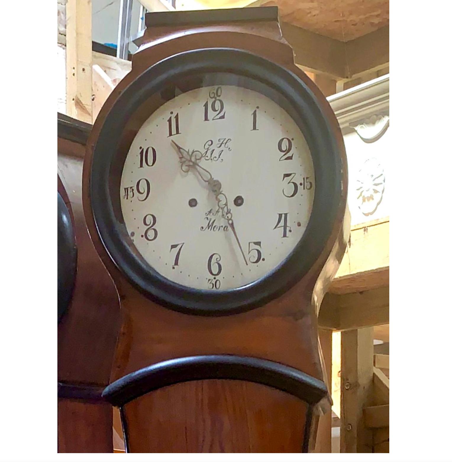 Antique Swedish mora clock from the early 1800s in Folk Art faux wood finish and simple detailing with a countryshape body and a roman numeral face in good condition. Measures: 205 cm.

It has the classic extended belly of a traditional Swedish mora