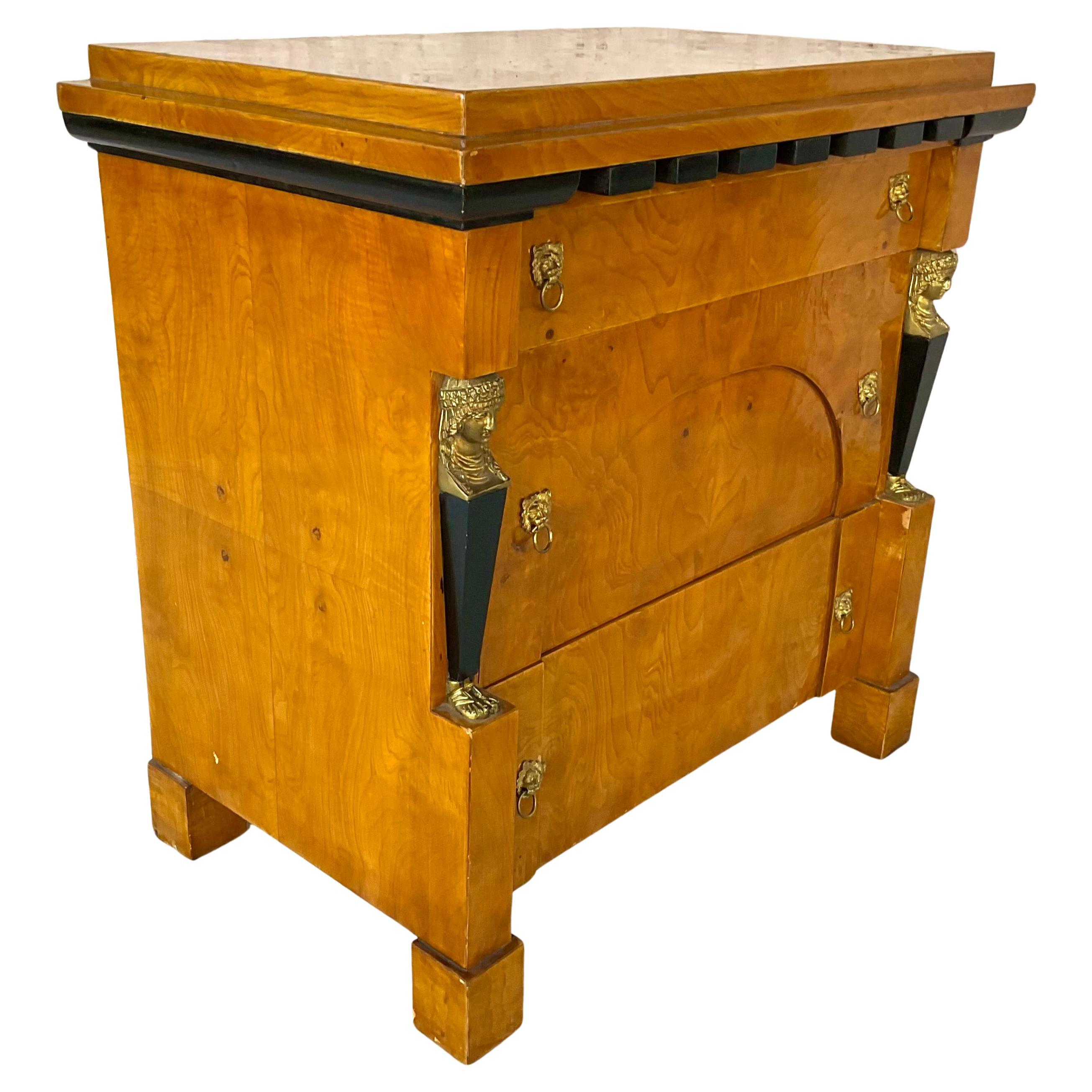 Elegante cassettiera neoclassica in stile Biedermeier. La cassettiera presenta tre ampi cassetti con tiretti a testa di leone in ottone dorato e pilastri decorativi figurati ebanizzati sormontati da busti femminili finemente fusi su ciascun lato. La