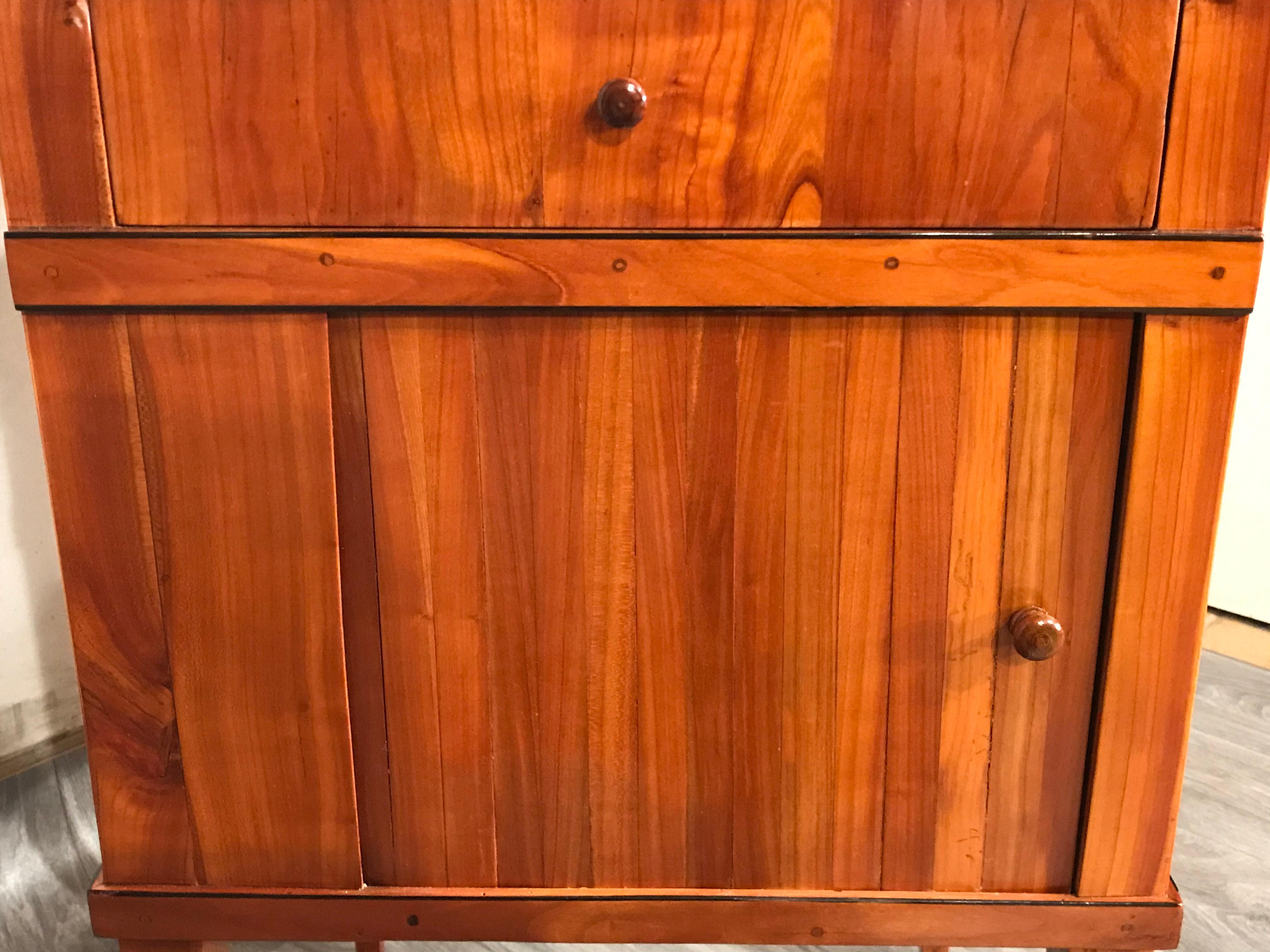 Biedermeier nightstand or small cabinet.
This beautiful night stand or small cabinet dates back to 1820 and comes from Southern Germany. It has a pretty blinds door and one drawer. An open work wooden gallery is framing the top. Cherrywood veneer