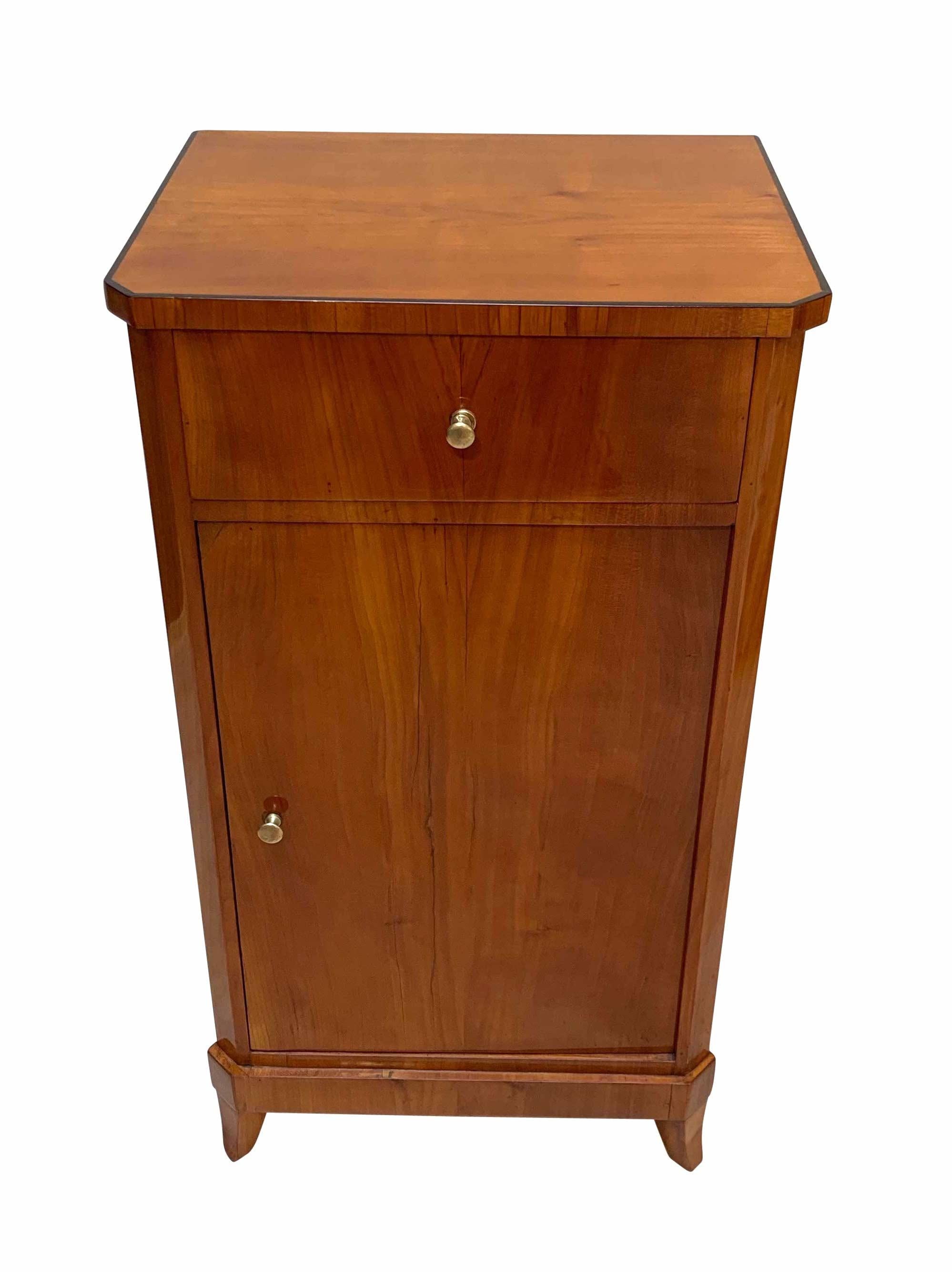 Small and very elegant Biedermeier nightstand / bedside table

Bookmatched cherry veneer, shellac hand-polished.

1 drawer and 1 door. Inside with 1 shelf. 
2 original brass knobs.