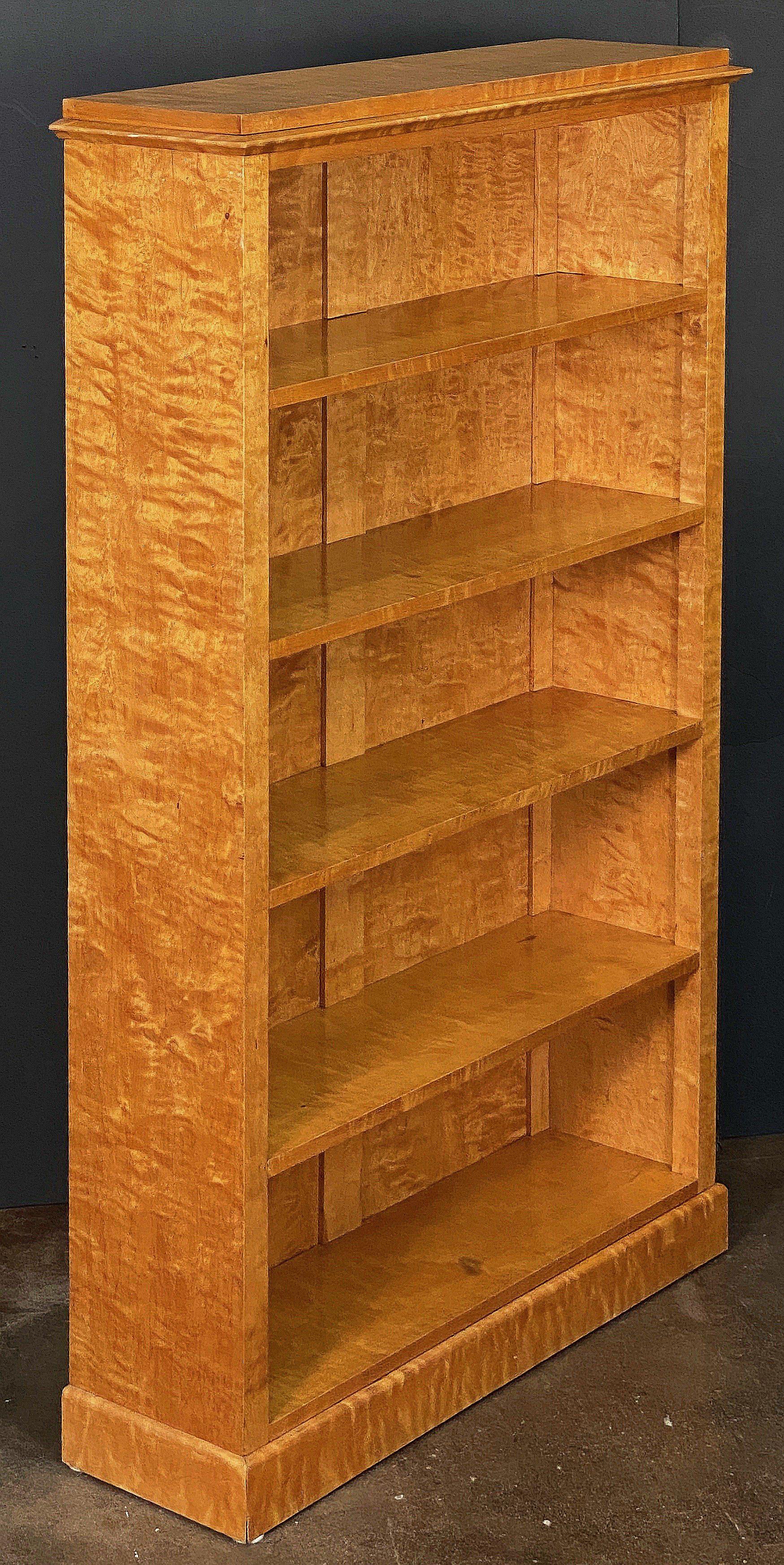 A fine English open bookcase (or set of shelves) in the Biedermeier style, featuring a moulded cornice top frieze of figured maple over five fitted shelves of curly maple, and resting on a raised plinth base.

