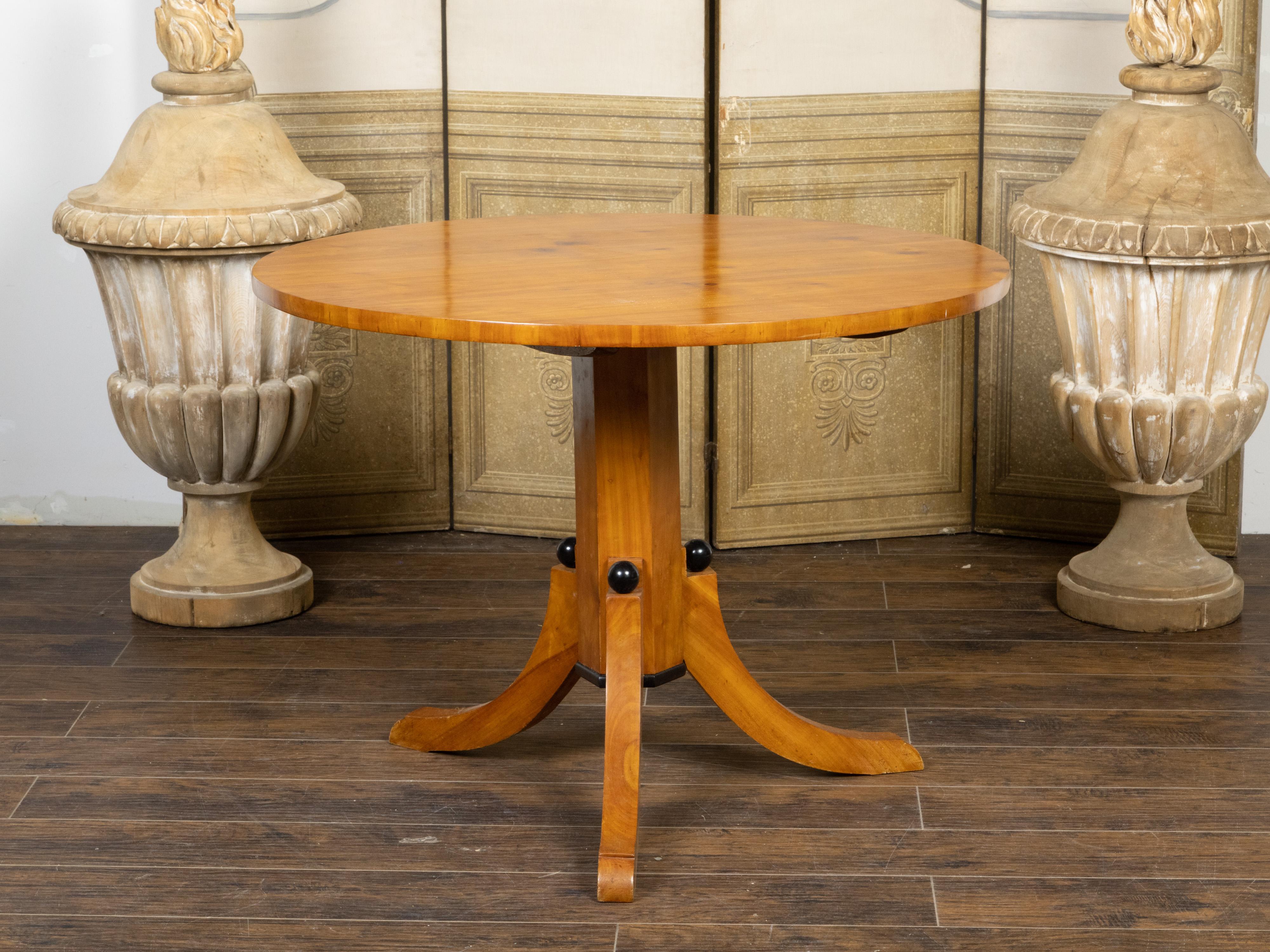 Table centrale en pin d'époque Biedermeier autrichienne du XIXe siècle, avec plateau circulaire, piédestal, base tripode et sphères ébonisées noires. Créée en Autriche pendant la période Biedermeier, cette table centrale en pin présente un plateau