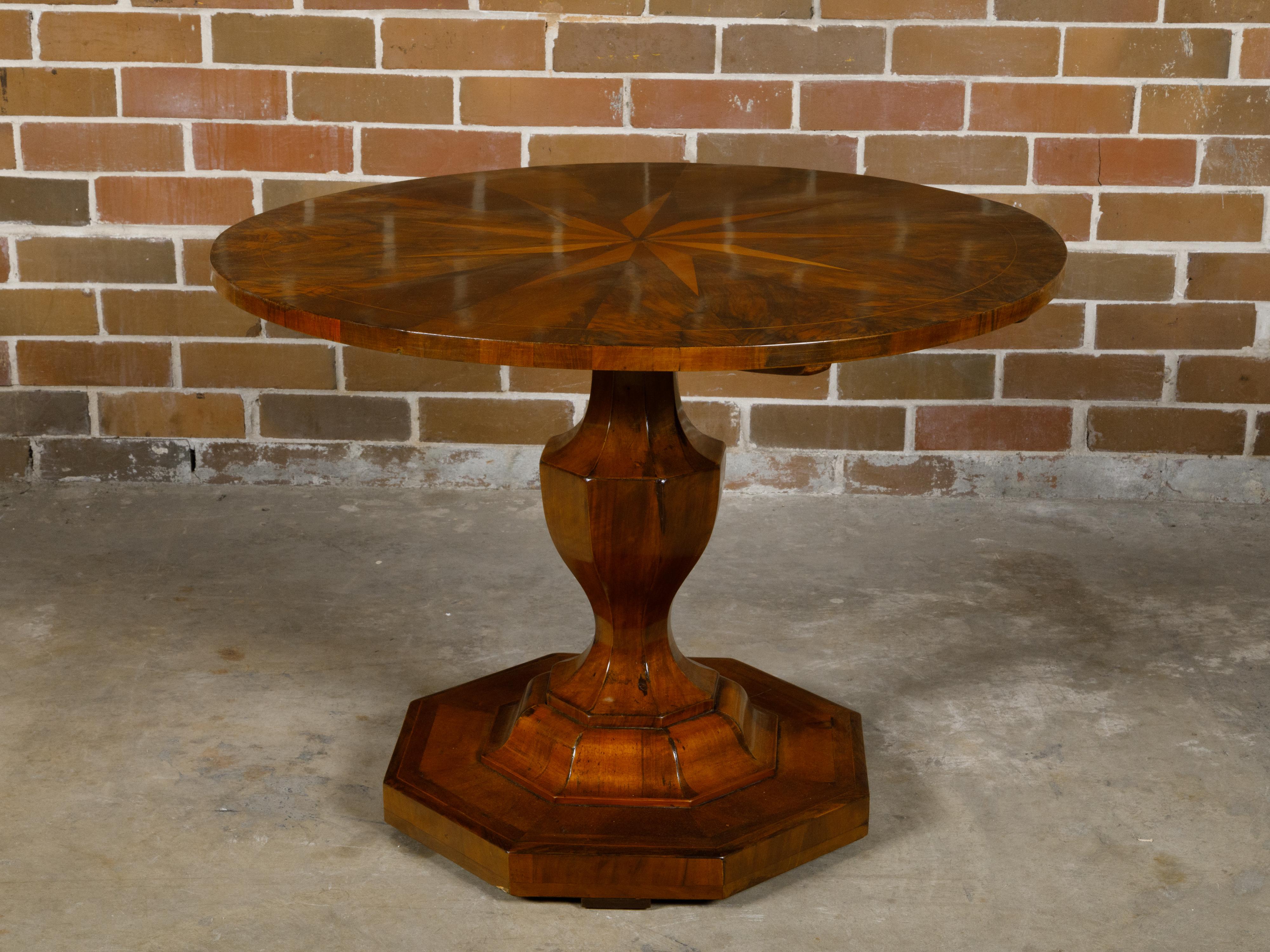 A Biedermeier period walnut center table from the 19th century with circular marquetry top, radiating motifs and pedestal base. This 19th-century Biedermeier period walnut center table is a masterpiece of design and craftsmanship, blending the