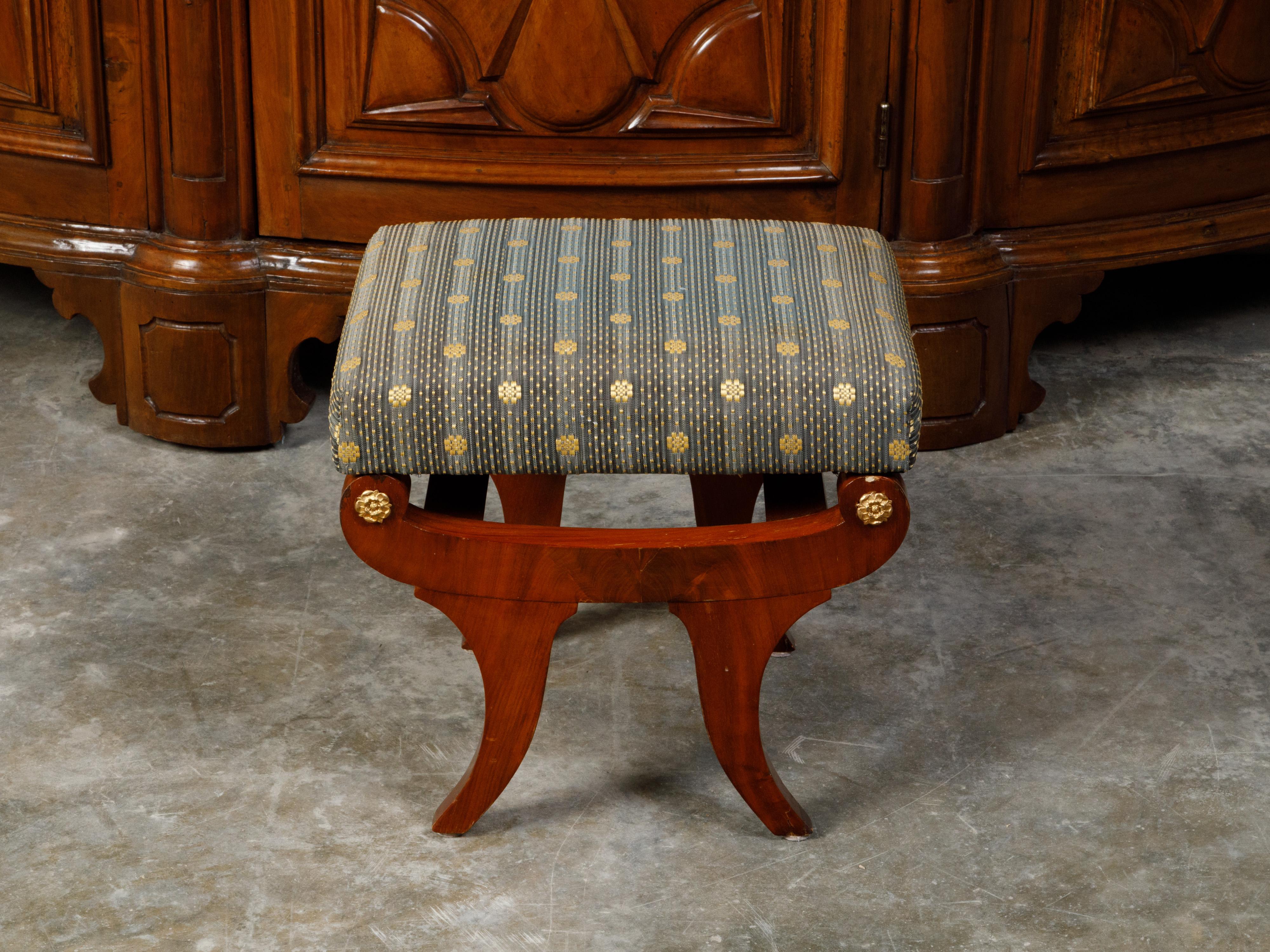 An Austrian Biedermeier period walnut stool from the 19th century, with upholstered seat and gilt rosettes. Created in Austria during the Biedermeier period, this walnut veneered stool features a rectangular upholstered seat, resting upon an elegant