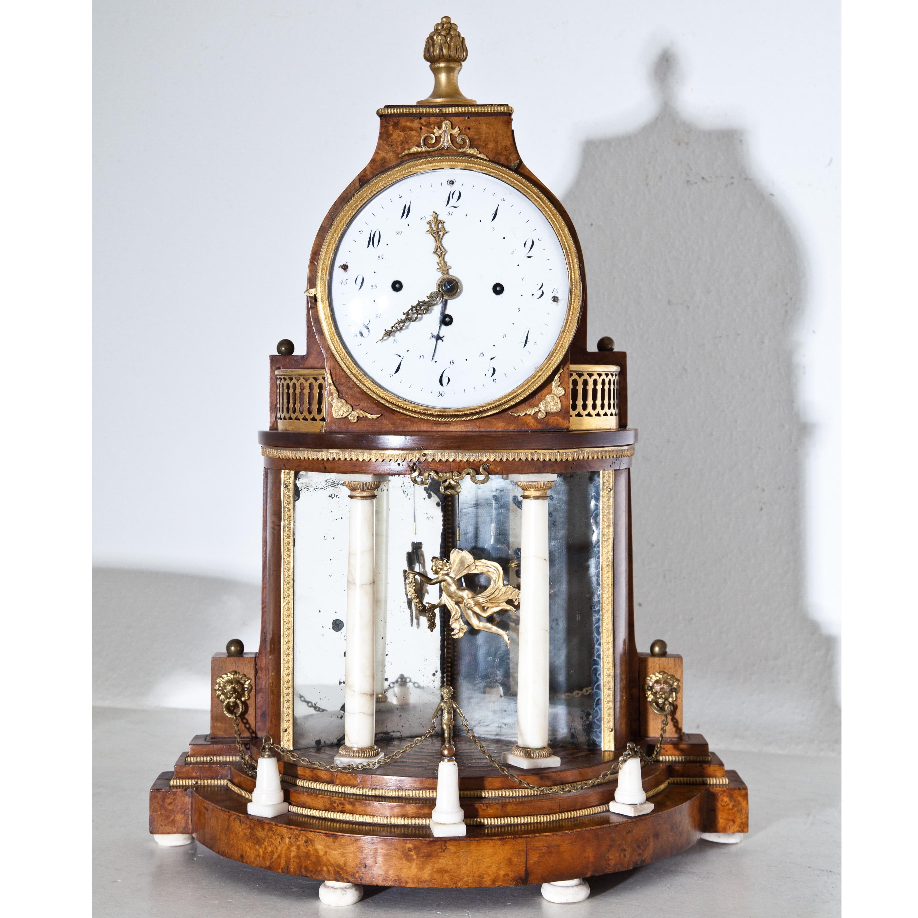 Biedermeier portal clock in an architecturally structured walnut case with alabaster columns, bronze fittings and mirrored rear wall. The clockwork with date and sound spiral. Pendulum in the shape of a winged putto.