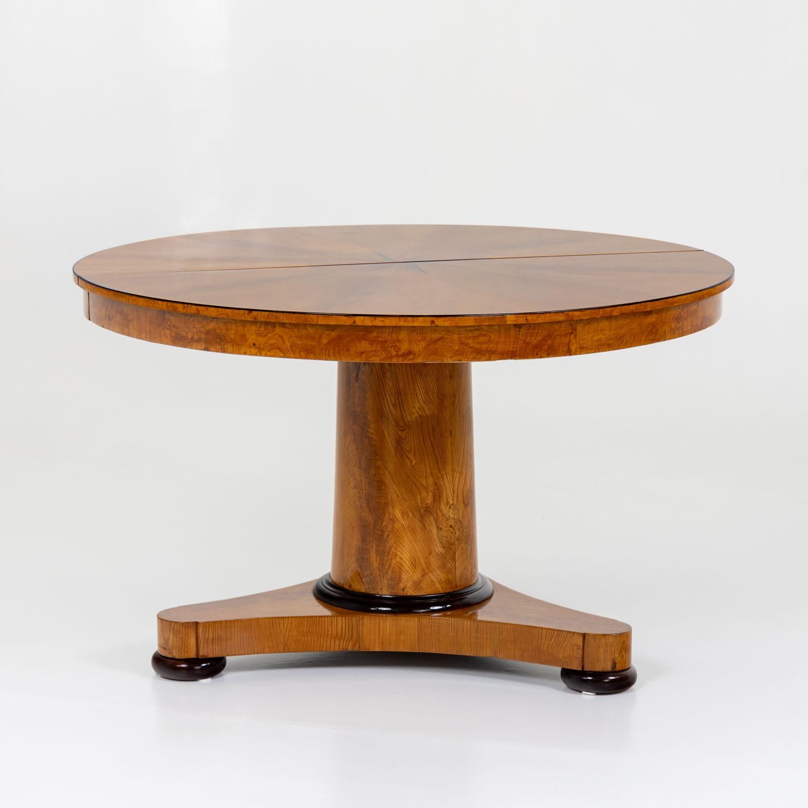 Biedermeier extending table with four inset tops and a maximum length of 320 cm. The table stands on a trefoil base with a strong, smooth central column and can be stabilized with fold-out conical legs if required. The table is veneered in ash and