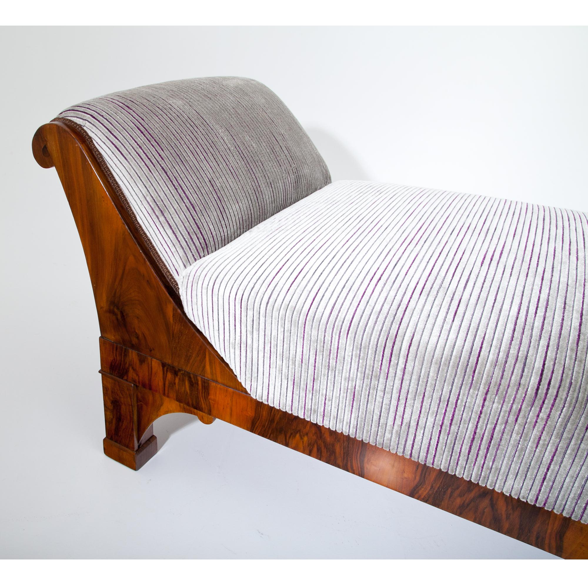 Large Biedermeier Recamiere standing on square feet. The recliner is in walnut veneered and has a curved back- and footrest. The Recamiere was professionally refurbished and reupholstered with a grey-violet striped fabric.