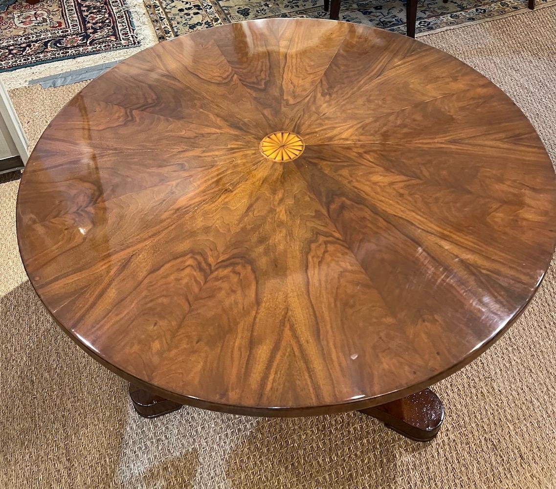 Beidermeier period round breakfast area table. It rests on a single supporting leg. The tabletop can flip and is secured by a small latch. 
Done with inlaid walnut wood. 

Austria, c. 1820s, diameter is 40