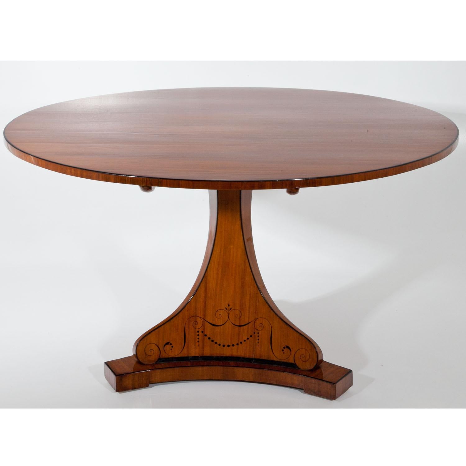 Large Biedermeier Salon table in the style of Dannhauser out of light mahogany. The table has a foldable top, stands on a trefoil base and is decorated with volutes.