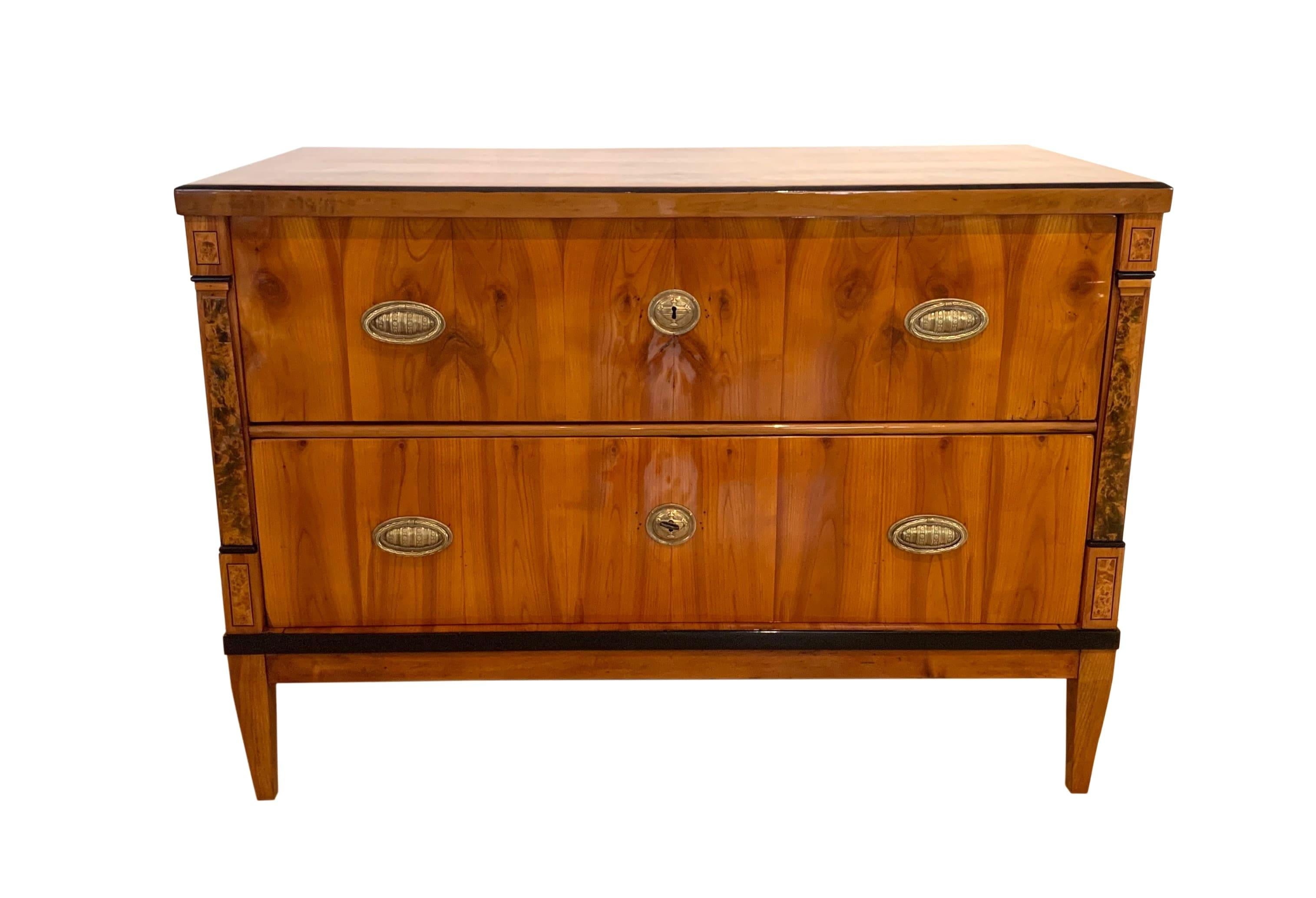 Very elegant neoclassical / early Biedermeier Saloon Commode / Chest of Two Drawers from South Germany about 1820.

Beautiful book-matched bright cherry veneer and solid wood, high-gloss french polished with shellac.

Ebonized edges of the plate.