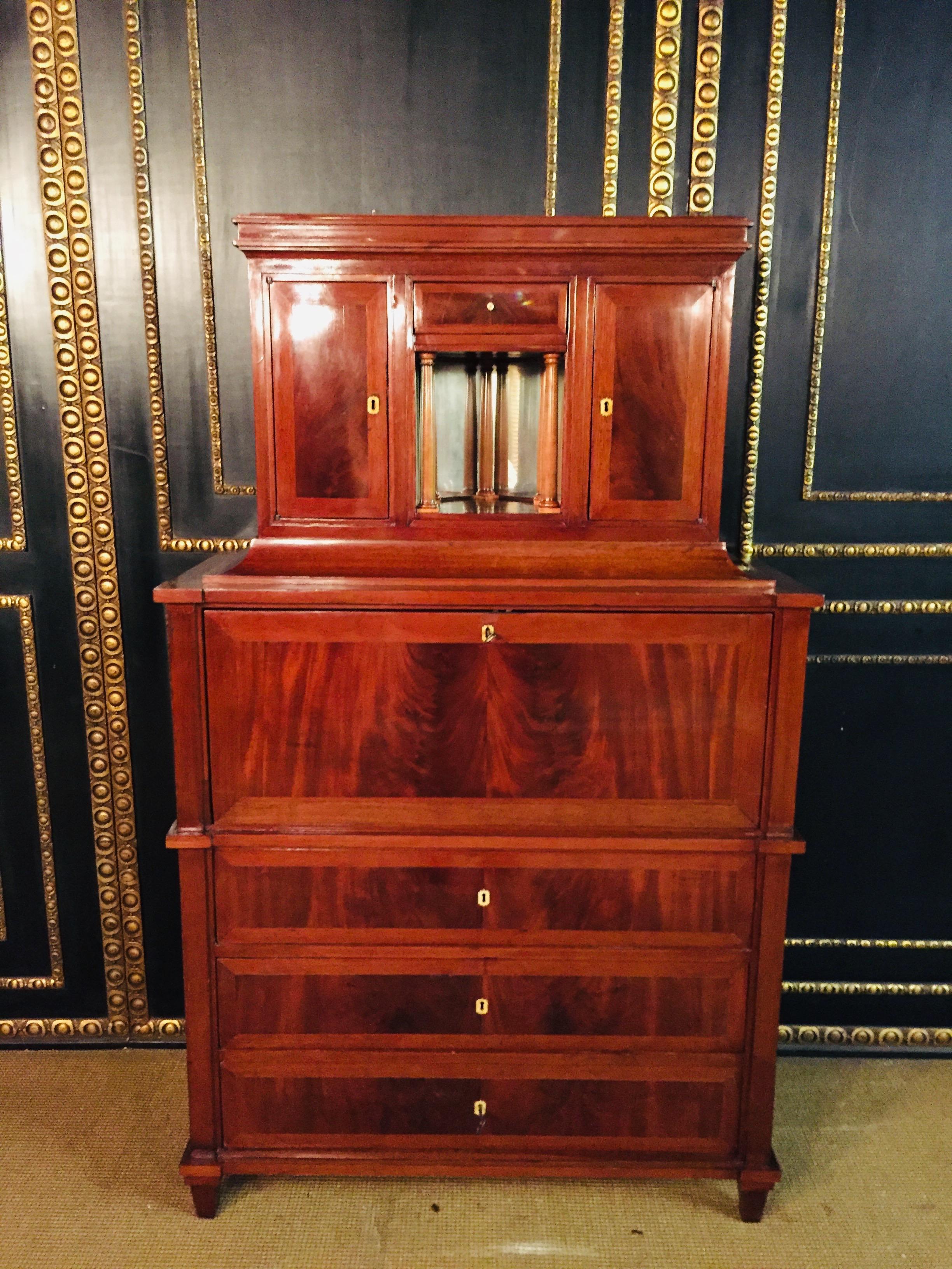 Caoba cubana de alta calidad sobre roble macizo . Cuerpo rectangular sobre patas puntiagudas. Provisto de tres cajones . Tablilla de escritura recta, detrás interior arquitectónico con 5 columnas. Adosado retranqueado de dos puertas con cornisa