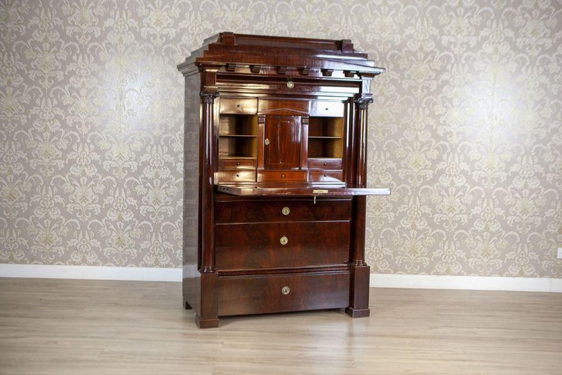 Biedermeier Antique Secretary Circa 1840 Veneered With Mahogany

Furniture in the Biedermeier style, made of soft wood veneered with mahogany, dated around 1840. The monumental shape of the piece, reminiscent of architectural structures, suggests a