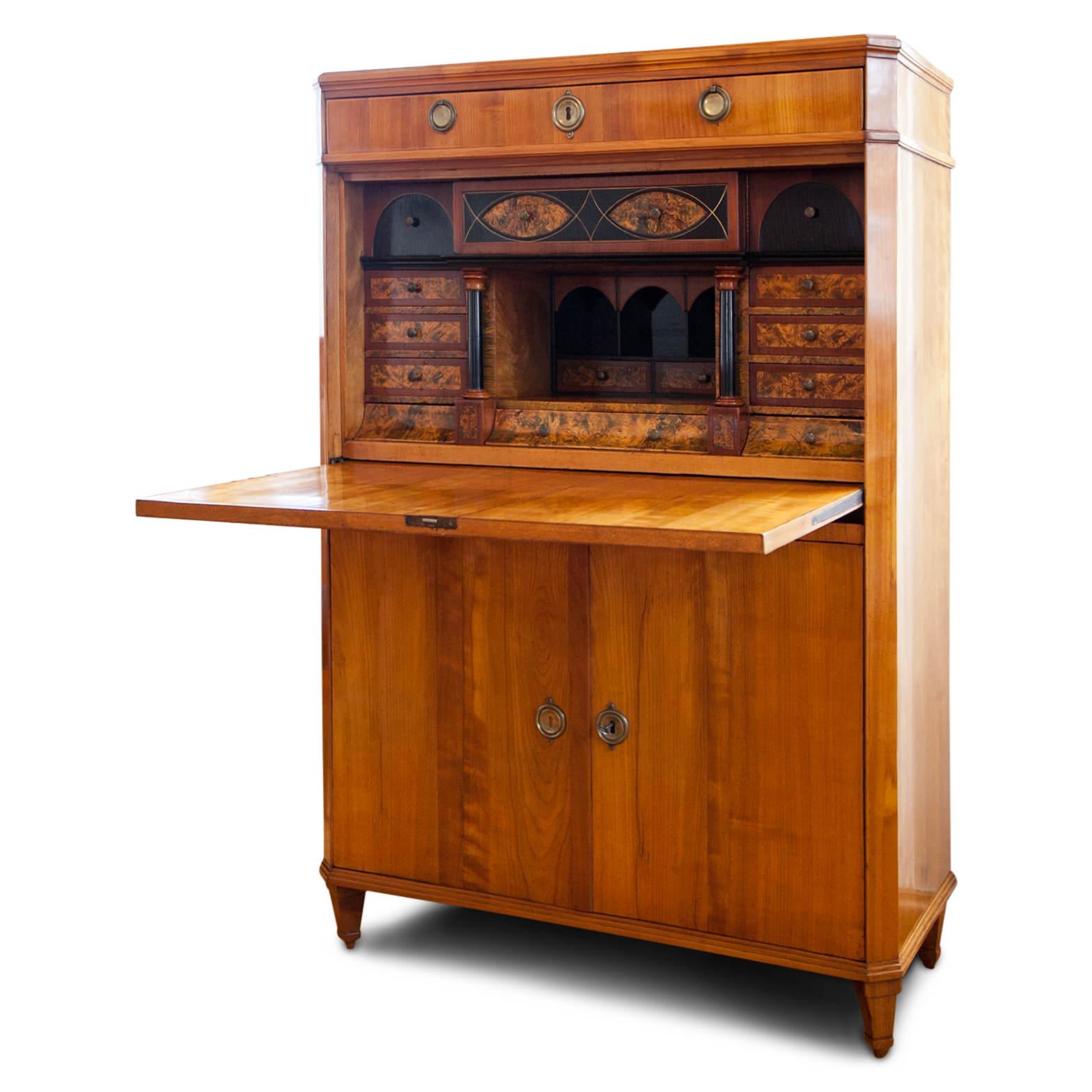 Secretaire of the early Biedermeier, circa 1810, with a two-doored base and a smooth exterior with one top shelf. The interior is beautifully veneered with burl wood and shows partly ebonized columns. Unrestored condition.