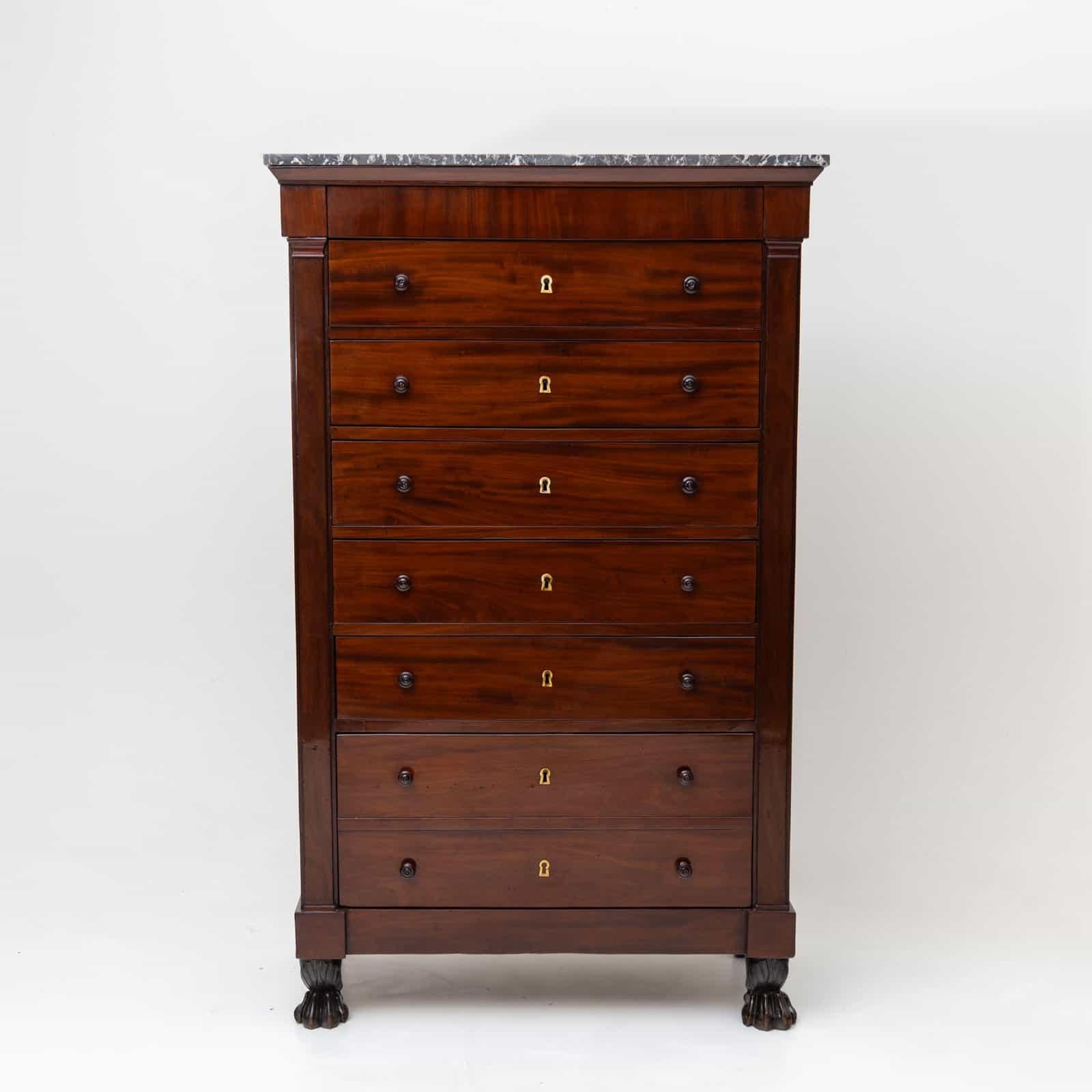 High chest of drawers or semainiere with seven large drawers and a concealed drawer under the marble top. The chest of drawers stands on carved lion paws and is accentuated by smooth pilasters on the sides. The body is veneered in mahogany and has