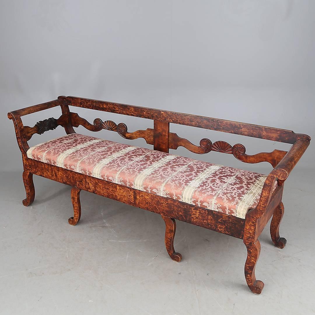 Beautiful and very unusual 19th century Swedish antique Biedermeier settle sofa in top grade quilted golden birch in a deep French polish finish with lovely carved detail.

It has delicate legs, backrest carvings and central shell motifs with a